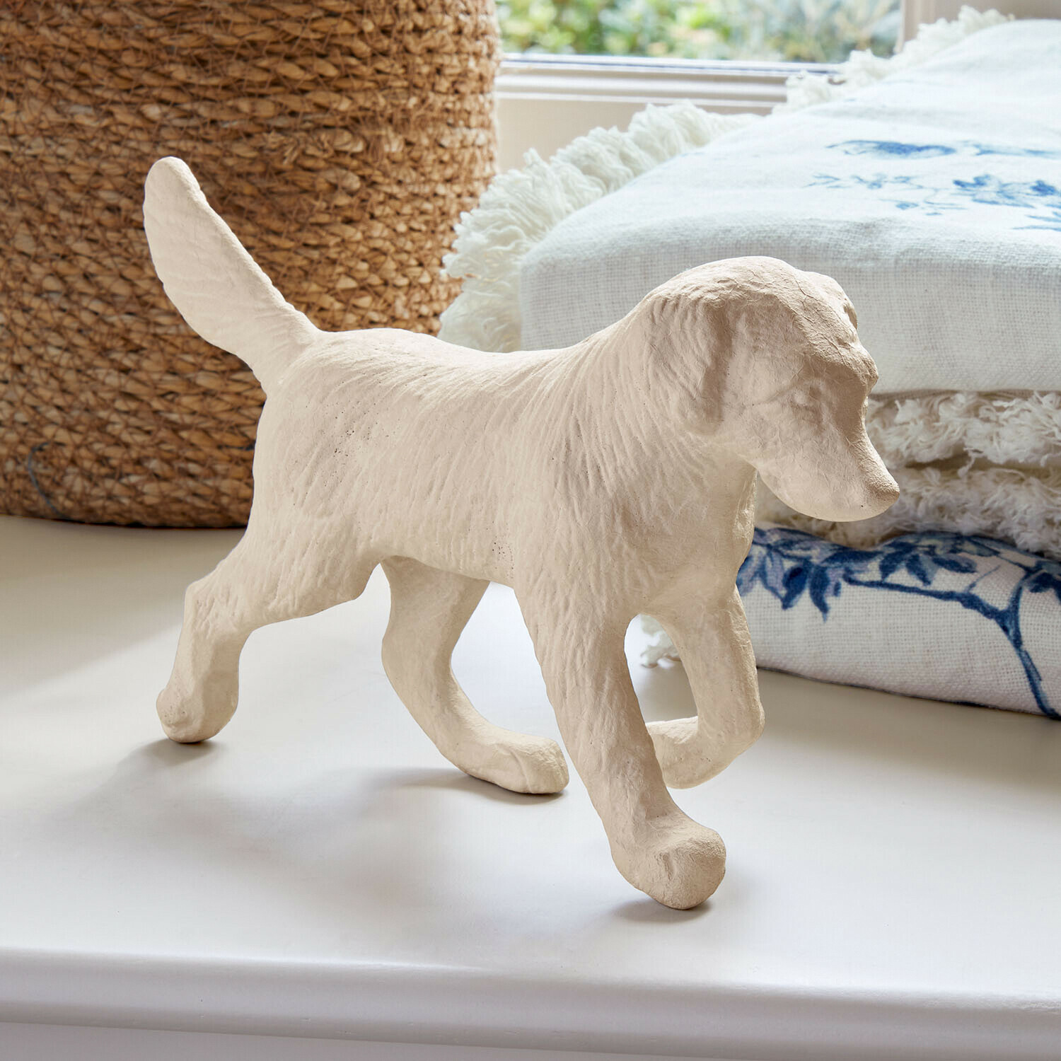 Deko-Hund Wendrel Helle Hundefigur aus strukturiertem Material auf weissem Untergrund mit dekorativem Stoff im Hintergrund