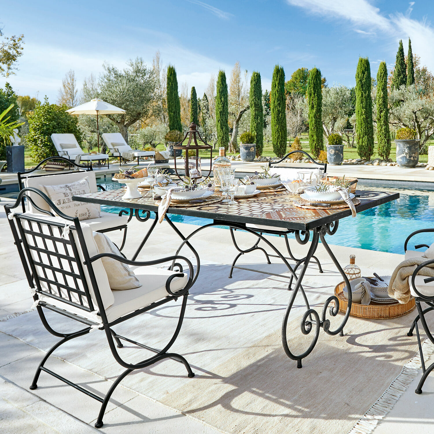 Tisch Grainville Gartenmöbel-Set aus Metall mit Mosaiktisch am Schwimmbecken an einem sonnigen Tag