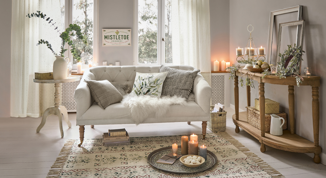 Gemütliches Wohnzimmer mit beigem Sofa, Holztisch und Kerzen auf dem Teppich, Winterdekoration