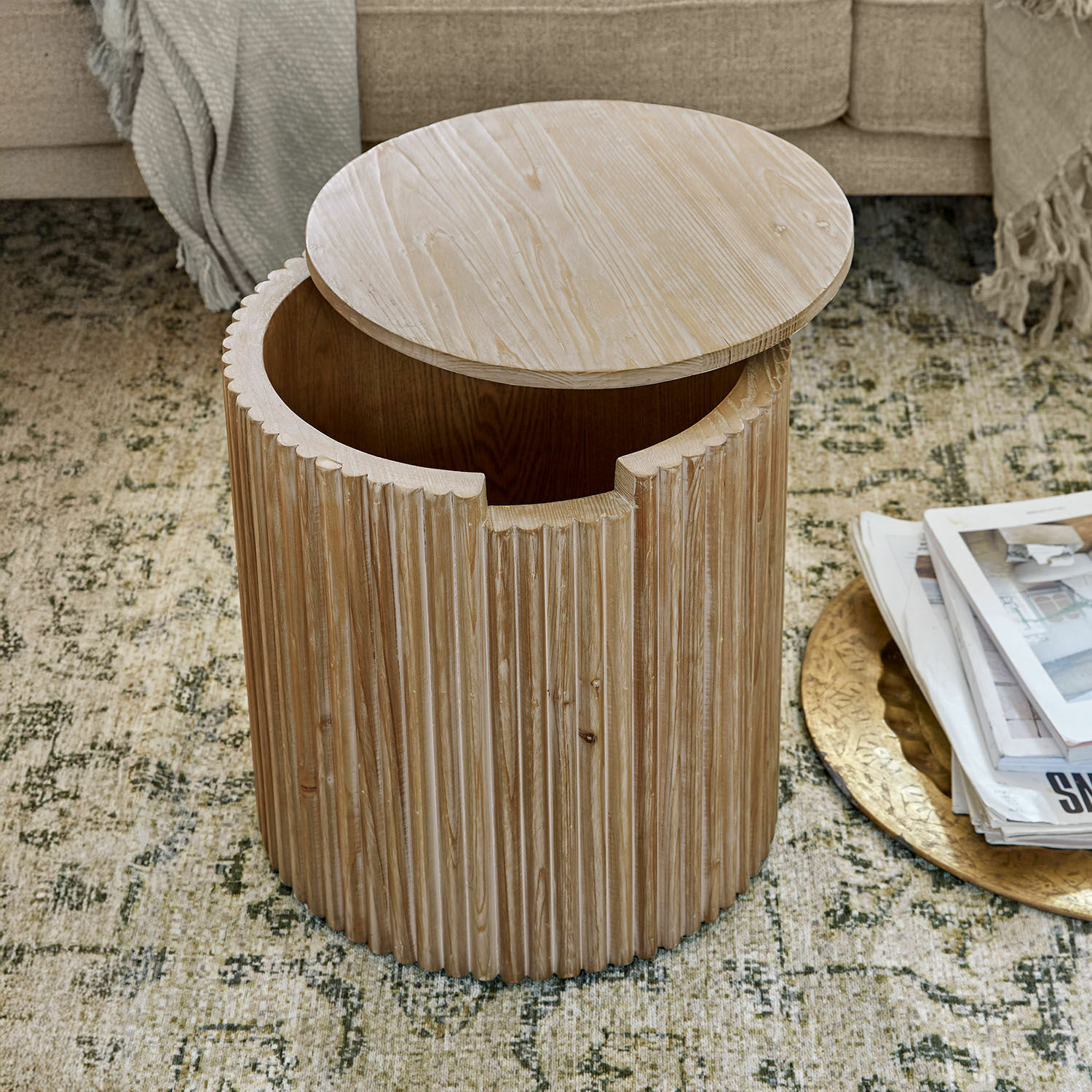 Beistelltisch Saintouré Runder Beistelltisch aus hellem Holz mit gerillter Oberfläche und praktischem Stauraum im Wohnzimmer.