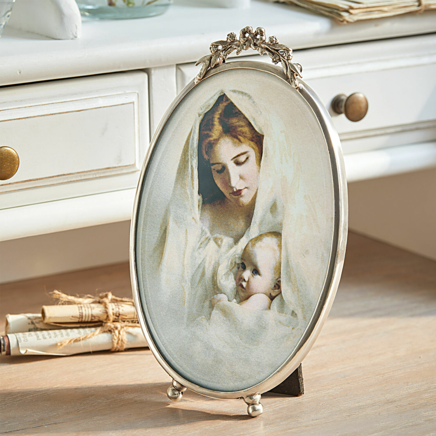 Bilderrahmen Grange Ovale Metallrahmen mit Bild einer Mutter und eines Babys in weissen Tüchern auf Holztisch