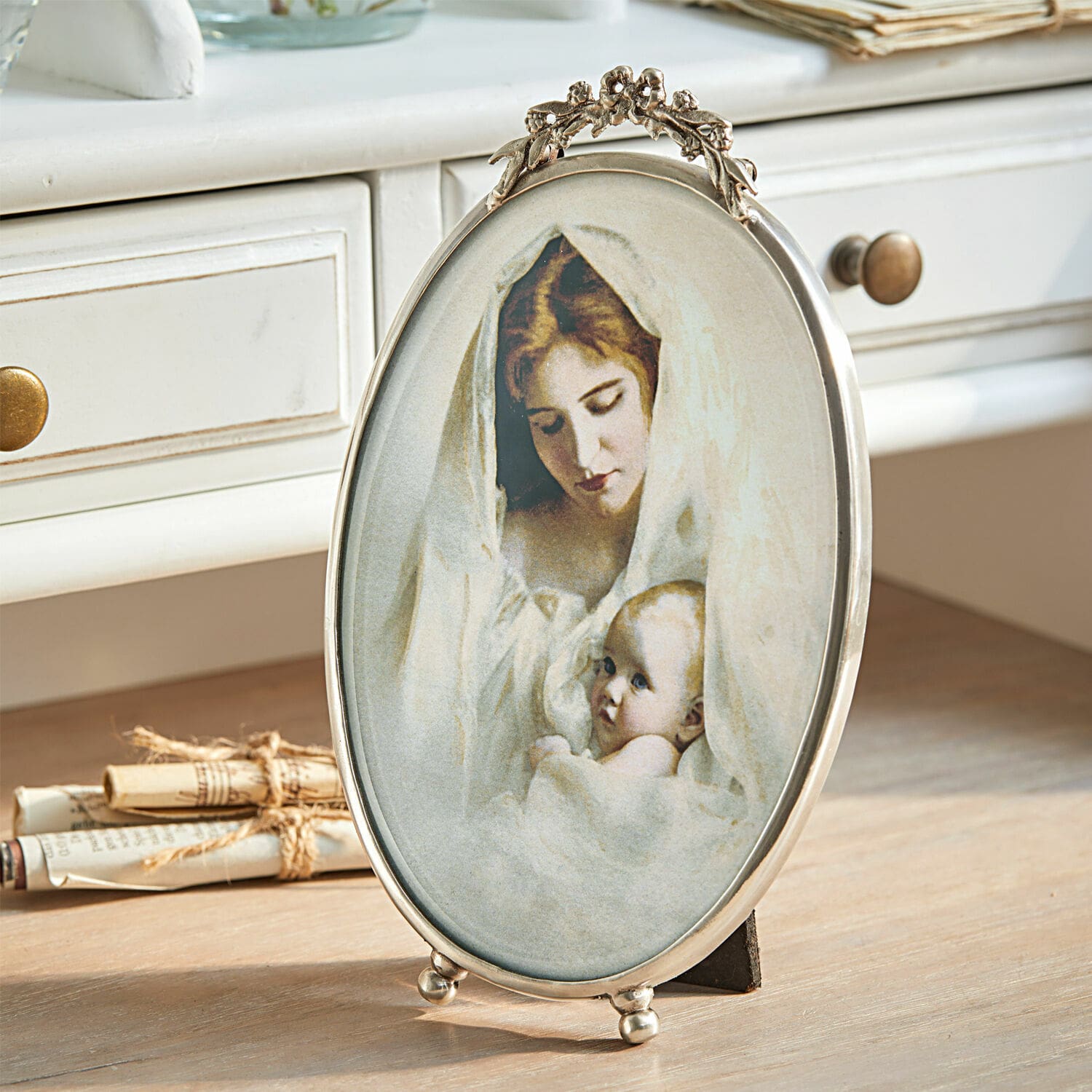 Bilderrahmen Grange Ovale Metallrahmen mit Bild einer Mutter und eines Babys in weissen Tüchern auf Holztisch