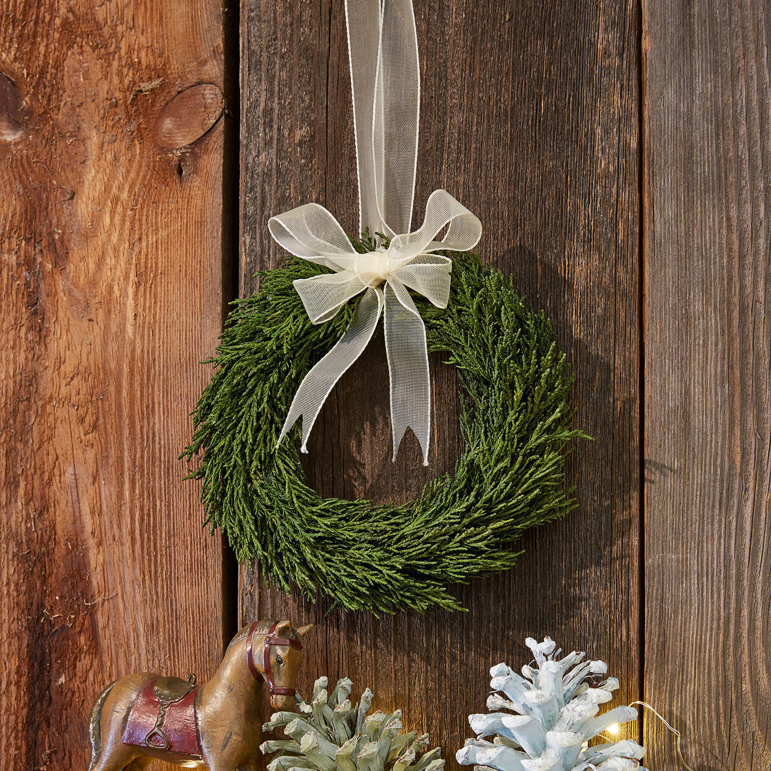 Kranz Sare Grüner Zweigkranz mit cremefarbenem Band an Holzwand, festliche Weihnachtsdekoration
