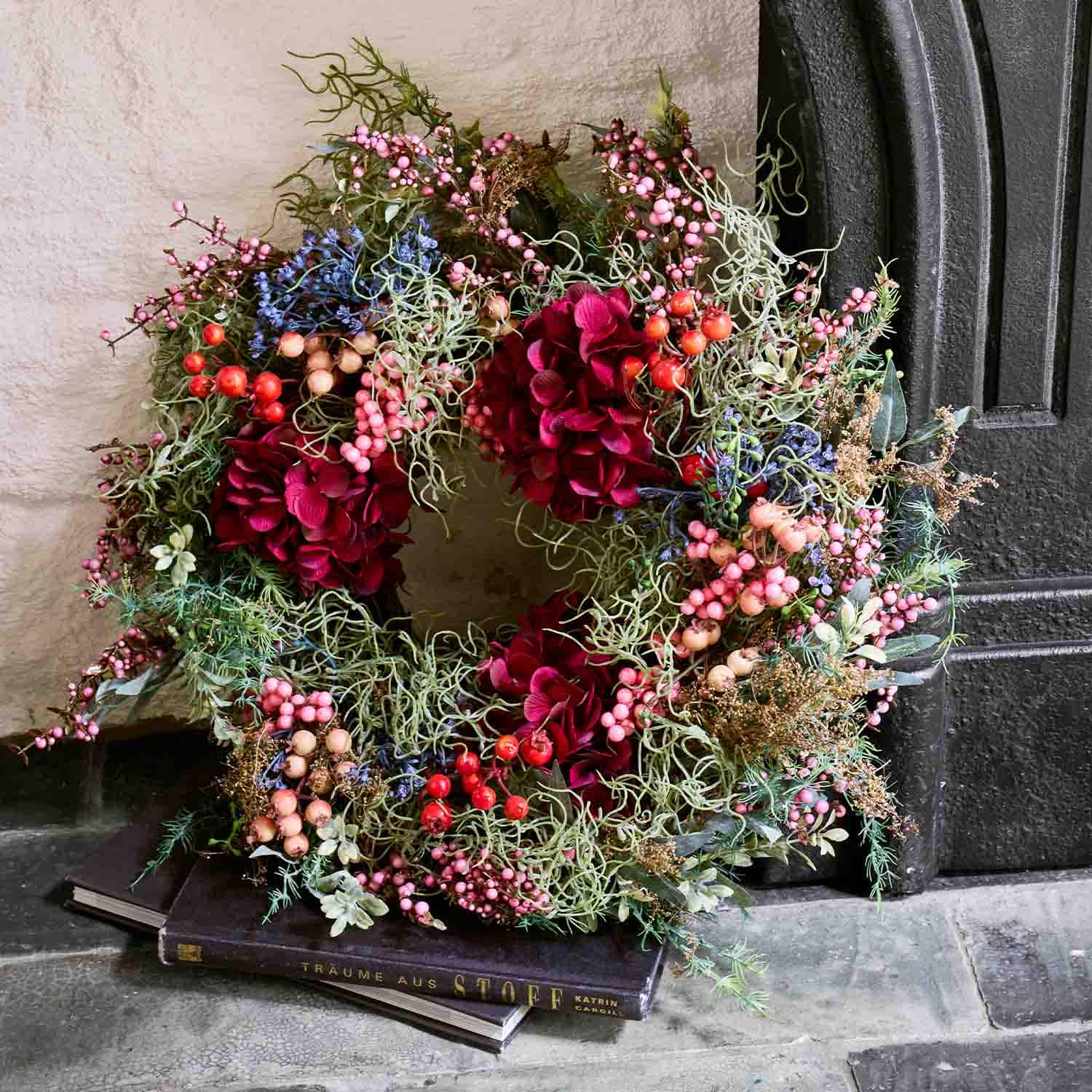Dekorativer Türkranz mit roten Blüten und bunten Beeren als saisonale Dekoration