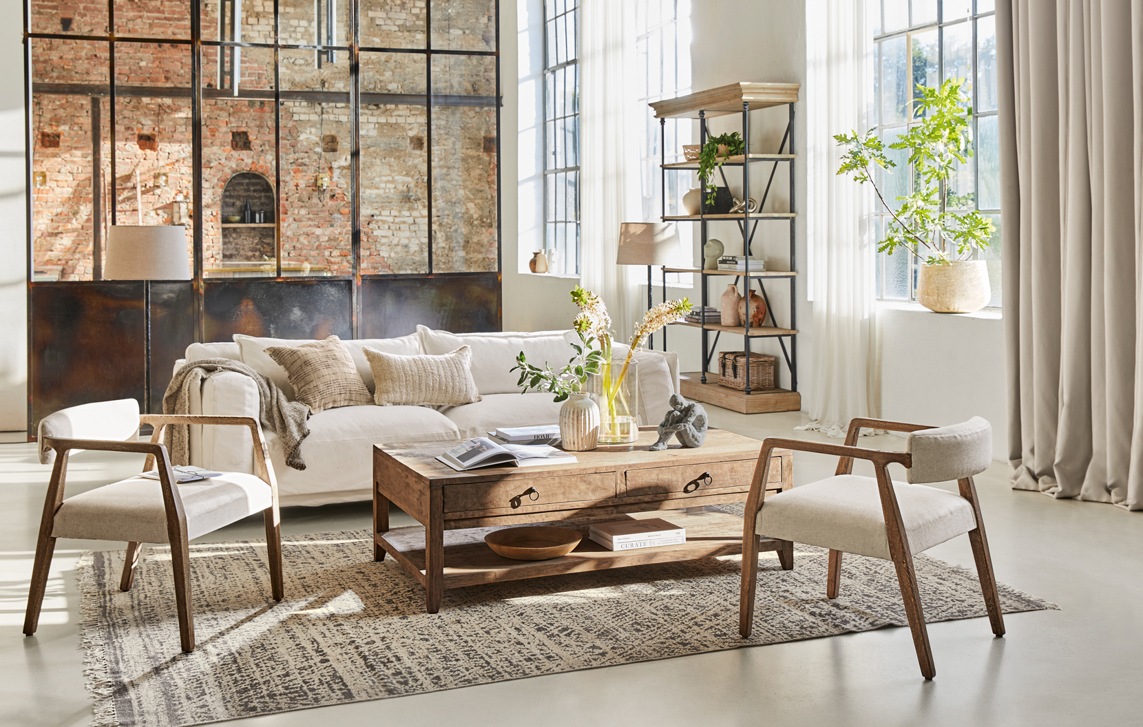 Gemütliches Loft-Wohnzimmer mit Holztisch, cremefarbener Couch und zwei Stühlen auf Teppichboden