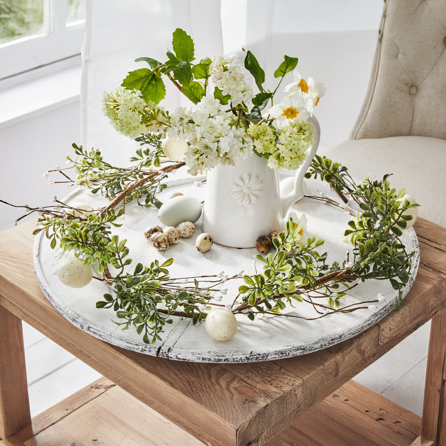 Girlande Antonin Dekorativer Kranz aus grünen Blättern und Eiern auf weißem Holztablett mit Keramikkrug und Blumen