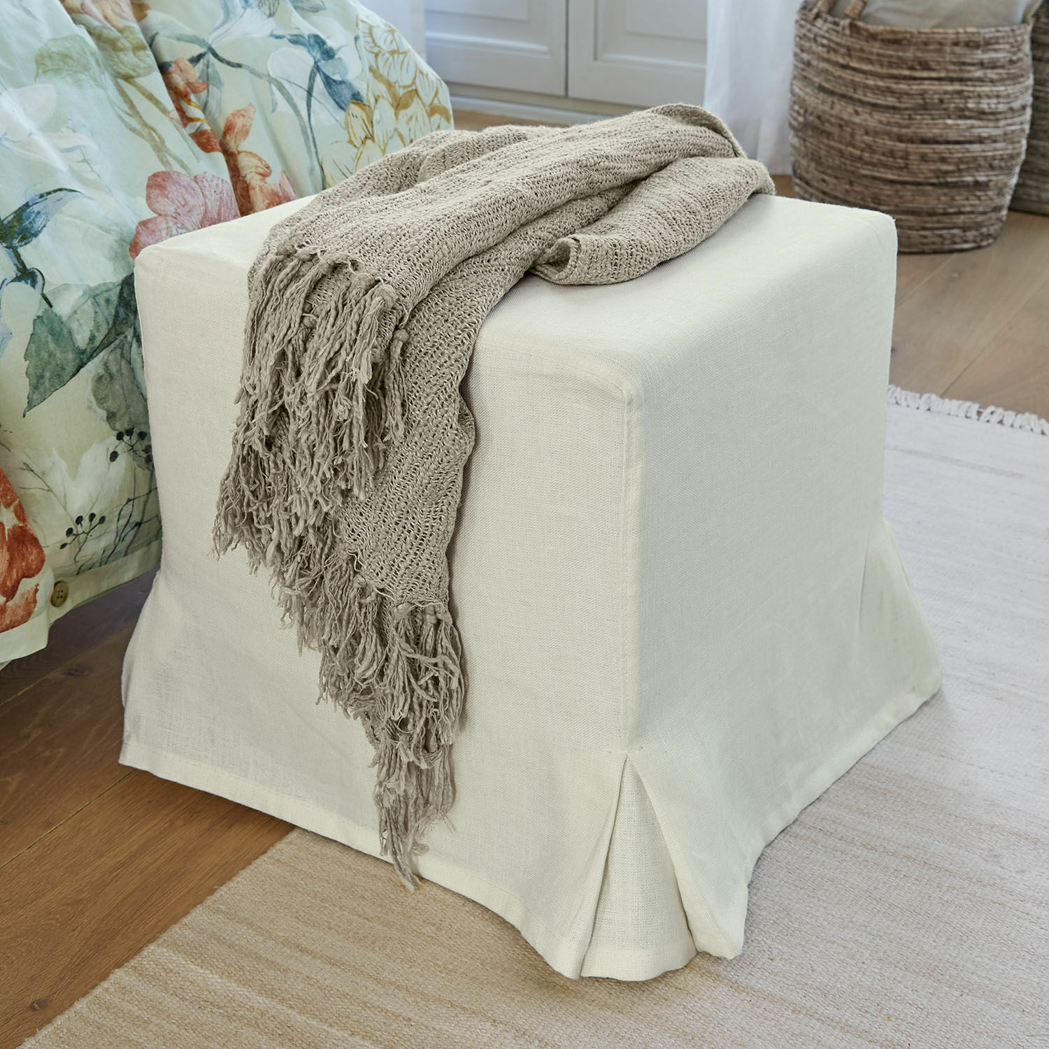 Hocker Ulysette Beiger Stoffhocker mit grauer Strickdecke auf Holzboden in gemütlichem Wohnzimmer