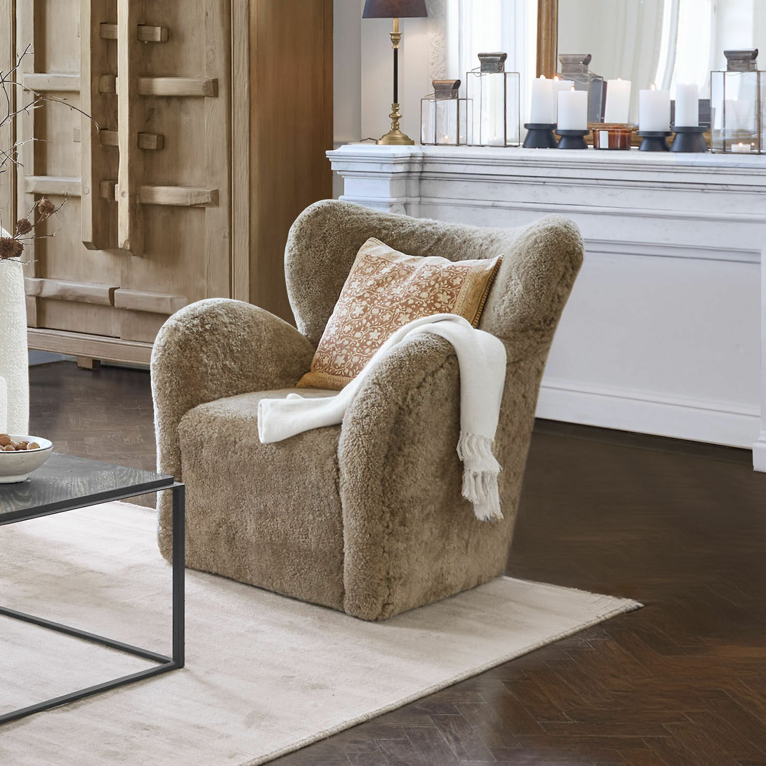 Sessel Ambrécourt Beiger Sessel aus weichem Material mit Kissen und weisser Decke im eleganten Wohnzimmer