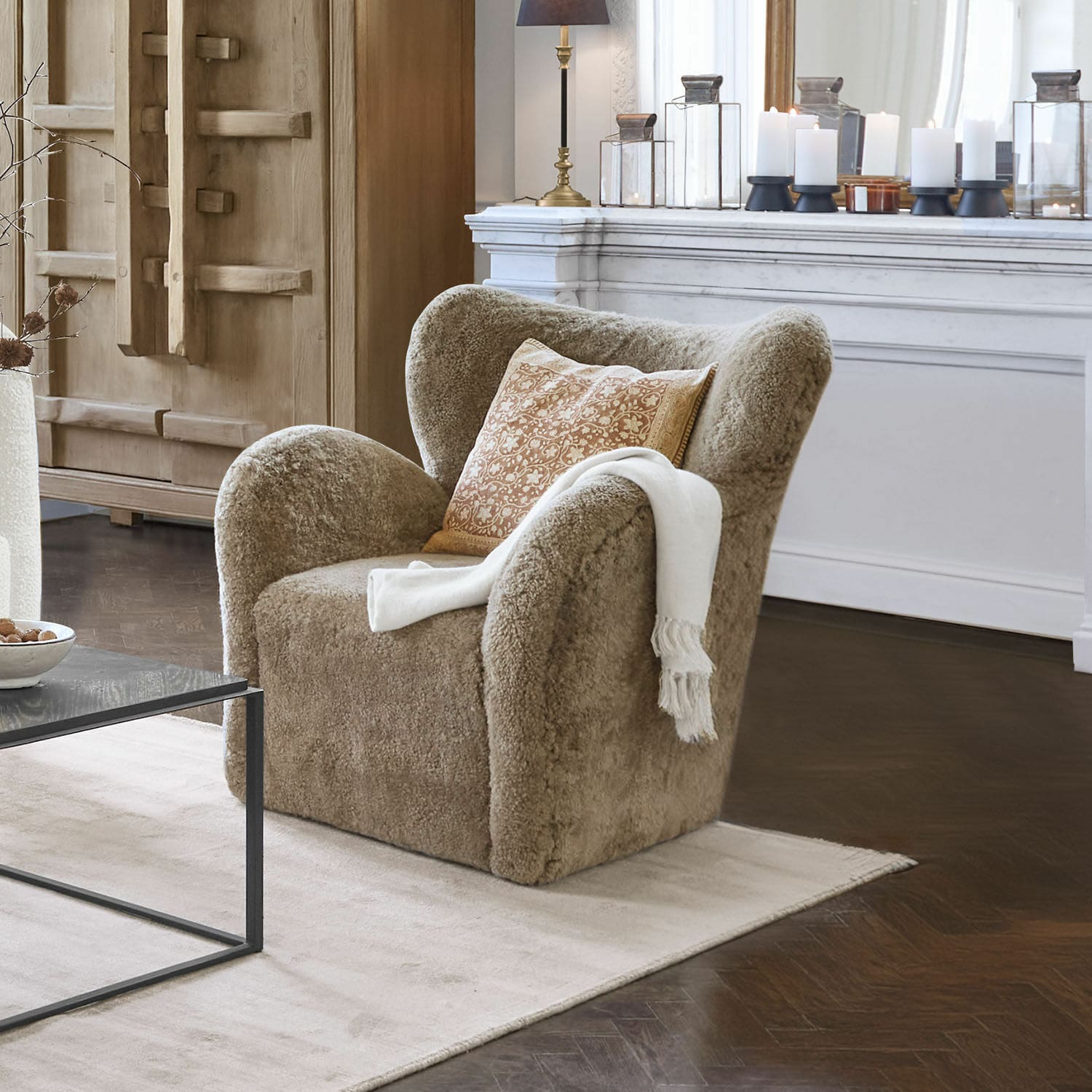 Sessel Ambrécourt Beiger Sessel aus weichem Material mit Kissen und weisser Decke im eleganten Wohnzimmer