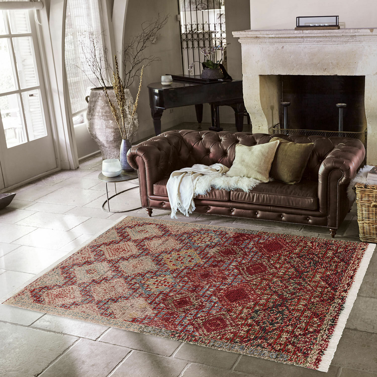 Teppich Thalivine Dekorativer Teppich in Rot-Beige mit Mustern auf Steinboden vor braunem Ledersofa.