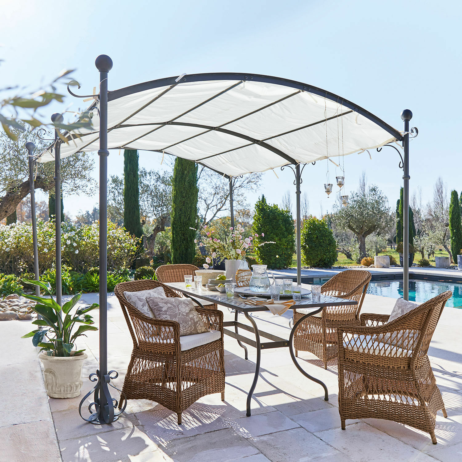 Pergola Yarl Gartenmöbel-Set aus braunem Rattan unter weissem Metallpavillon neben dem Schwimmbecken