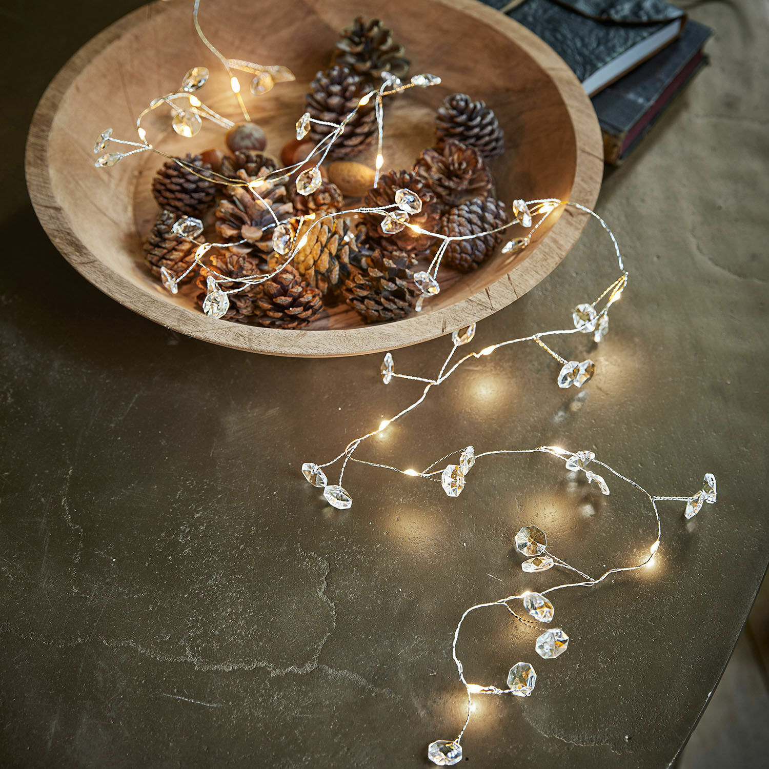 Lichterkette Laurits Holzschale mit Zapfen und zarter Lichterkette mit Kristallanhängern auf dem Tisch