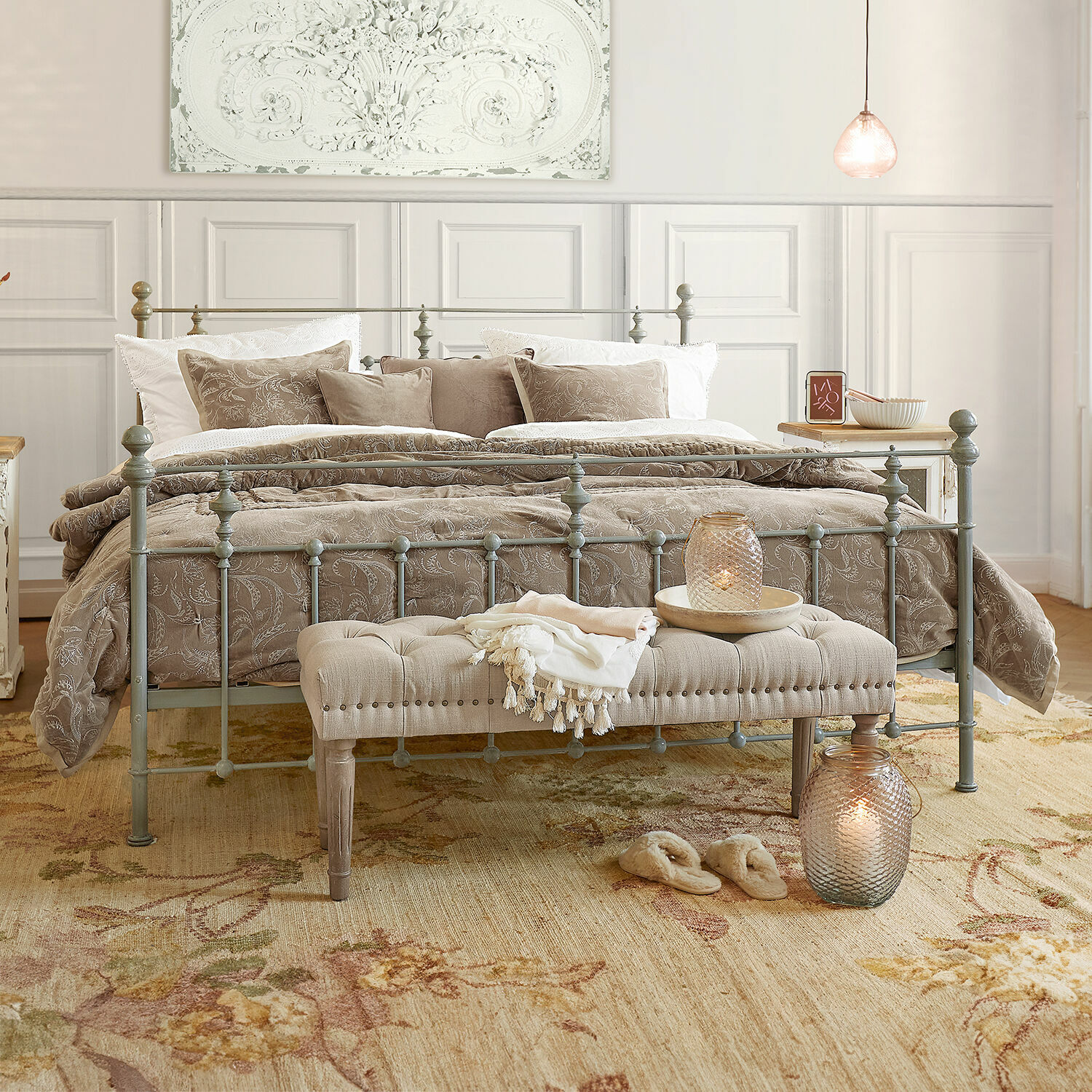Bett Beauvierre Schlafzimmer mit grauem Metallbett, beiger Bettwäsche mit Blumenmuster und gepolsterter Bank am Fussteil