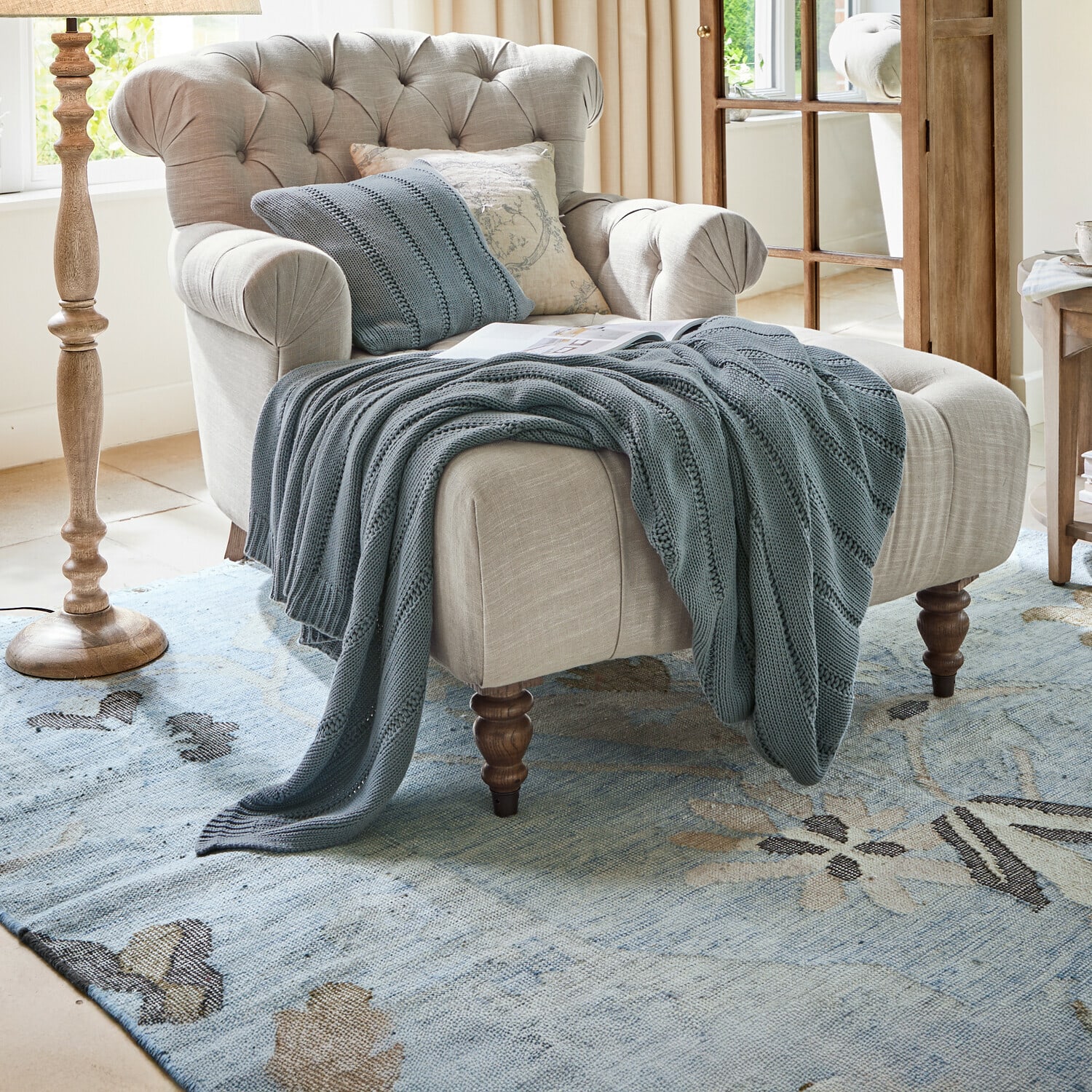 Plaid Lémeré Beiger Polstersessel mit gesteppter Rückenlehne und blauem Strickplaid im Wohnzimmer