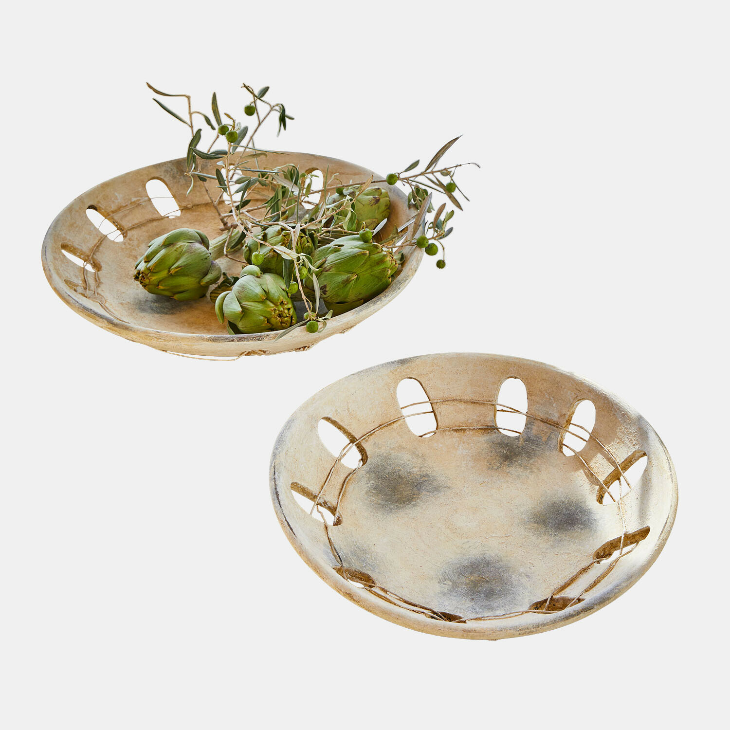 Zwei dekorative beige Keramikschalen mit Öffnungen, eine gefüllt mit grünen Artischocken