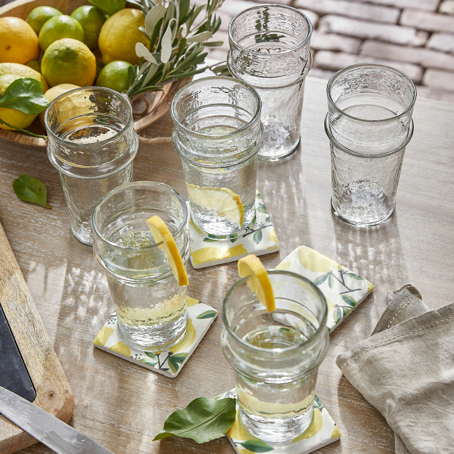Glas 6er Set Avrilla Klarglas-Gläser mit Struktur, teils mit Zitronenscheiben, auf Holztisch mit Zitrusfrüchten