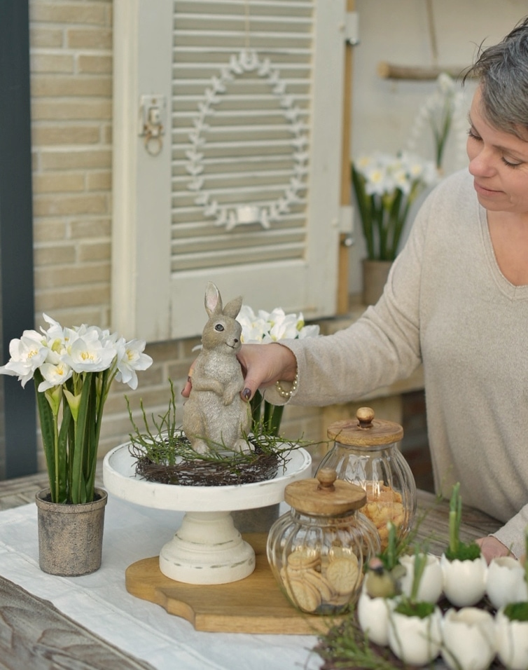 Natürliche Osterdekoration mit Hasenfigur, weissen Blumen und Glasbehältern für Guetzli