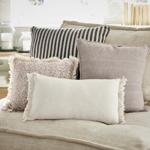 Vier dekorative Kissen in neutralen Farben auf dem beigen Sofa, Wohntextilien für das Wohnzimmer