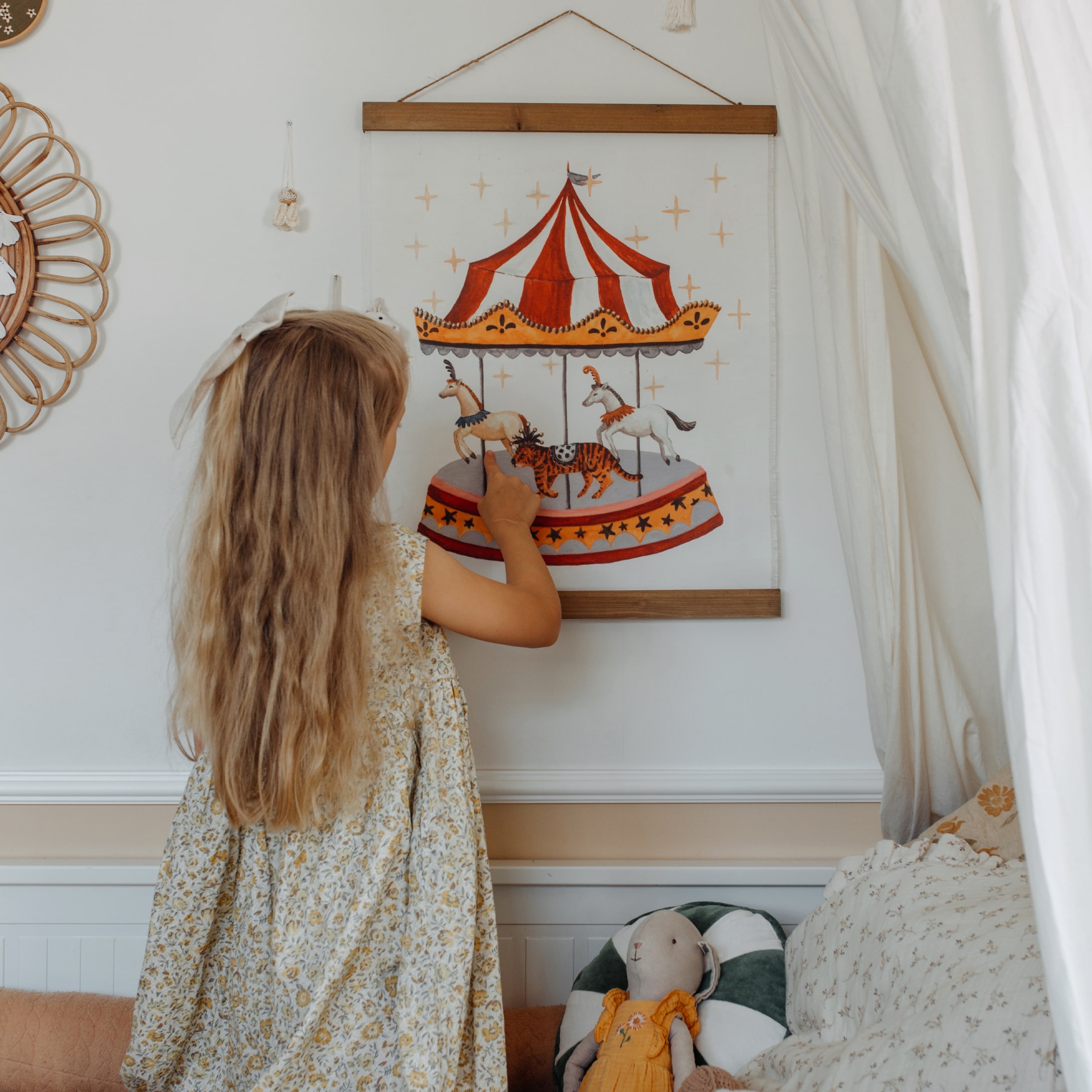 Kind berührt rot-weisses Karussell-Wandbild im gemütlichen Kinderzimmer
