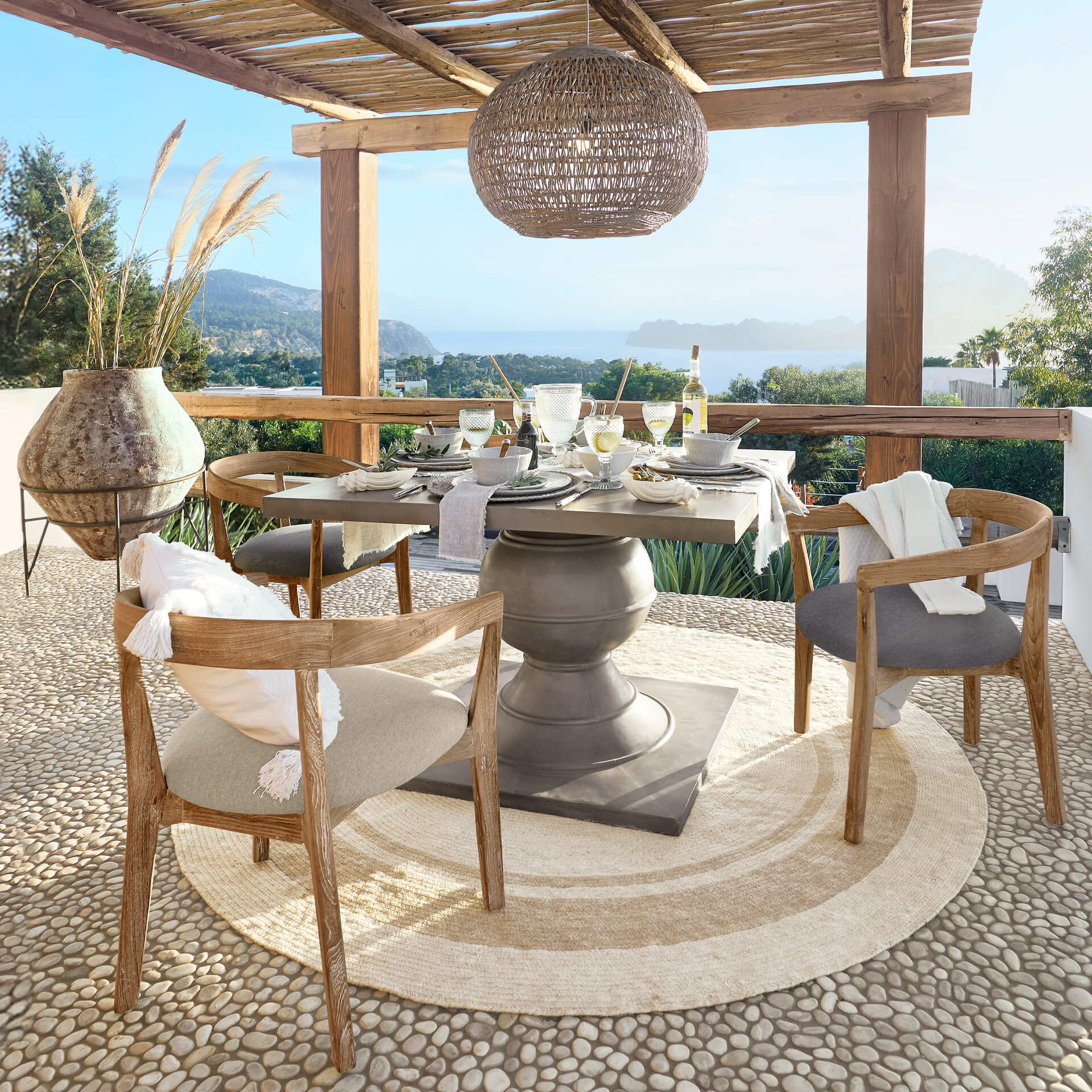 Gartentisch mit Betonsockel und Holzstühlen auf der Terrasse mit Meerblick