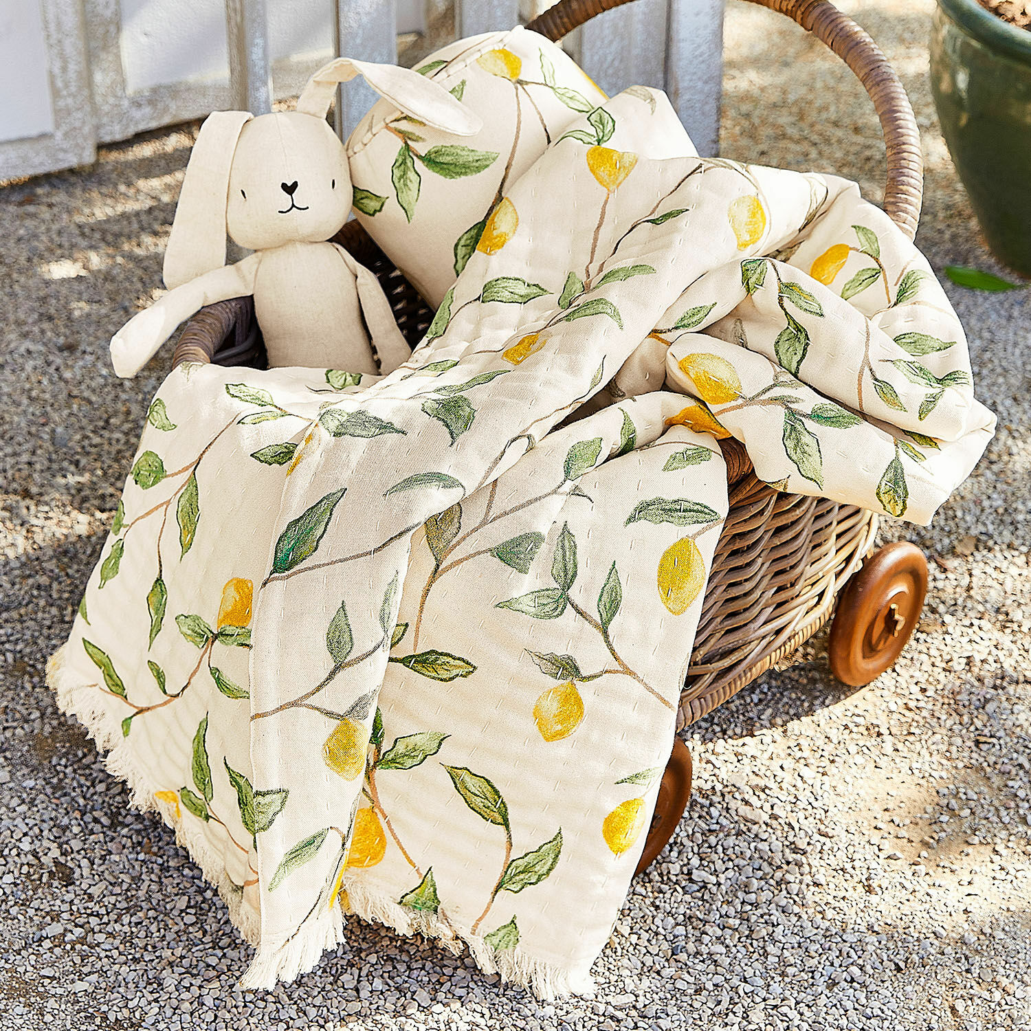 Plaid Palerina Baumwolldecke in Creme mit gelben Zitronen und grünen Blättern im Korb aus Rattan
