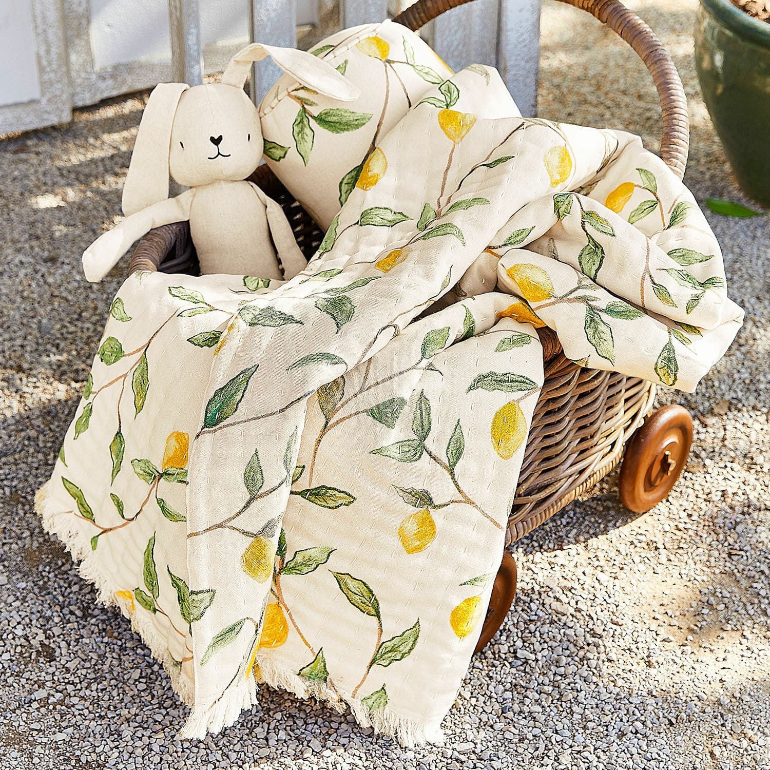 Plaid Palerina Baumwolldecke in Creme mit gelben Zitronen und grünen Blättern im Korb aus Rattan