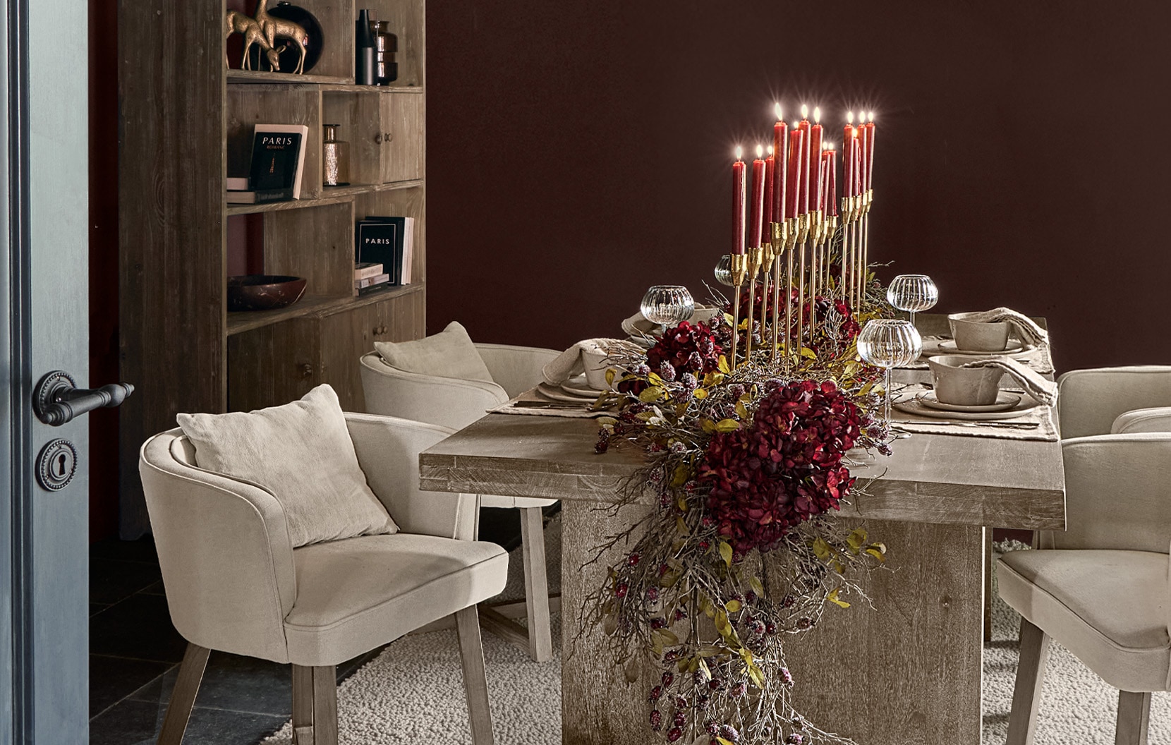 Esszimmer mit Holztisch, cremefarbenen Sesseln und roter Kerzen- und Blumendekoration in der Tischmitte