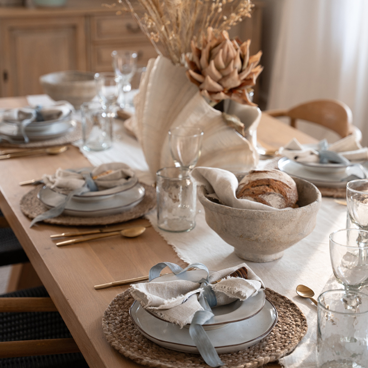 Rustikaler Holztisch mit Keramiktellern, Leinenservietten und getrockneten Blumen als Tischdekoration