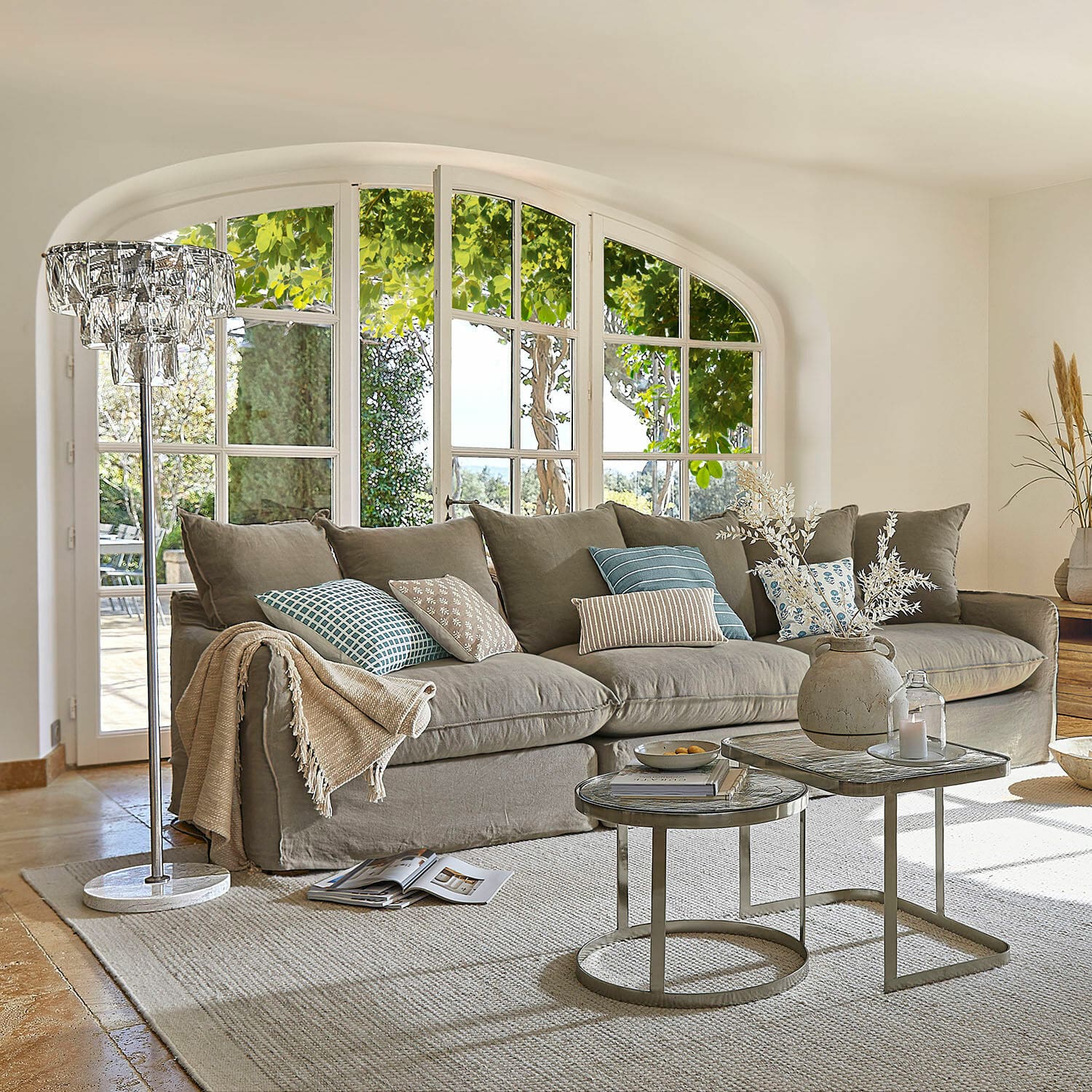 Sofa Finchingfield Gemütliches graues Sofa mit Kissen und Beistelltischen im hellen Wohnzimmer mit grossen Fenstern