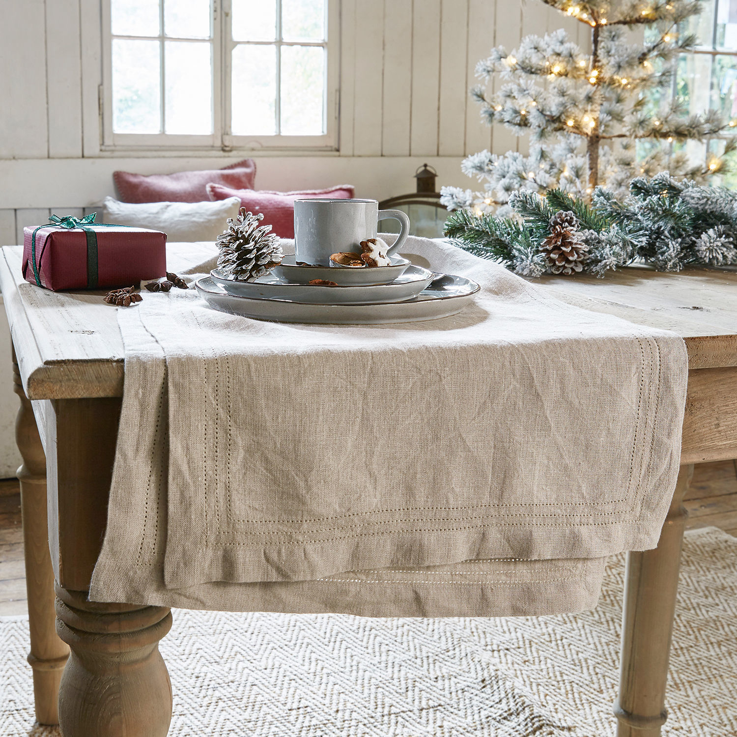 Tischläufer Brion Beiger Leinen-Tischläufer auf Holztisch mit Weihnachtsdekoration und grauem Geschirr