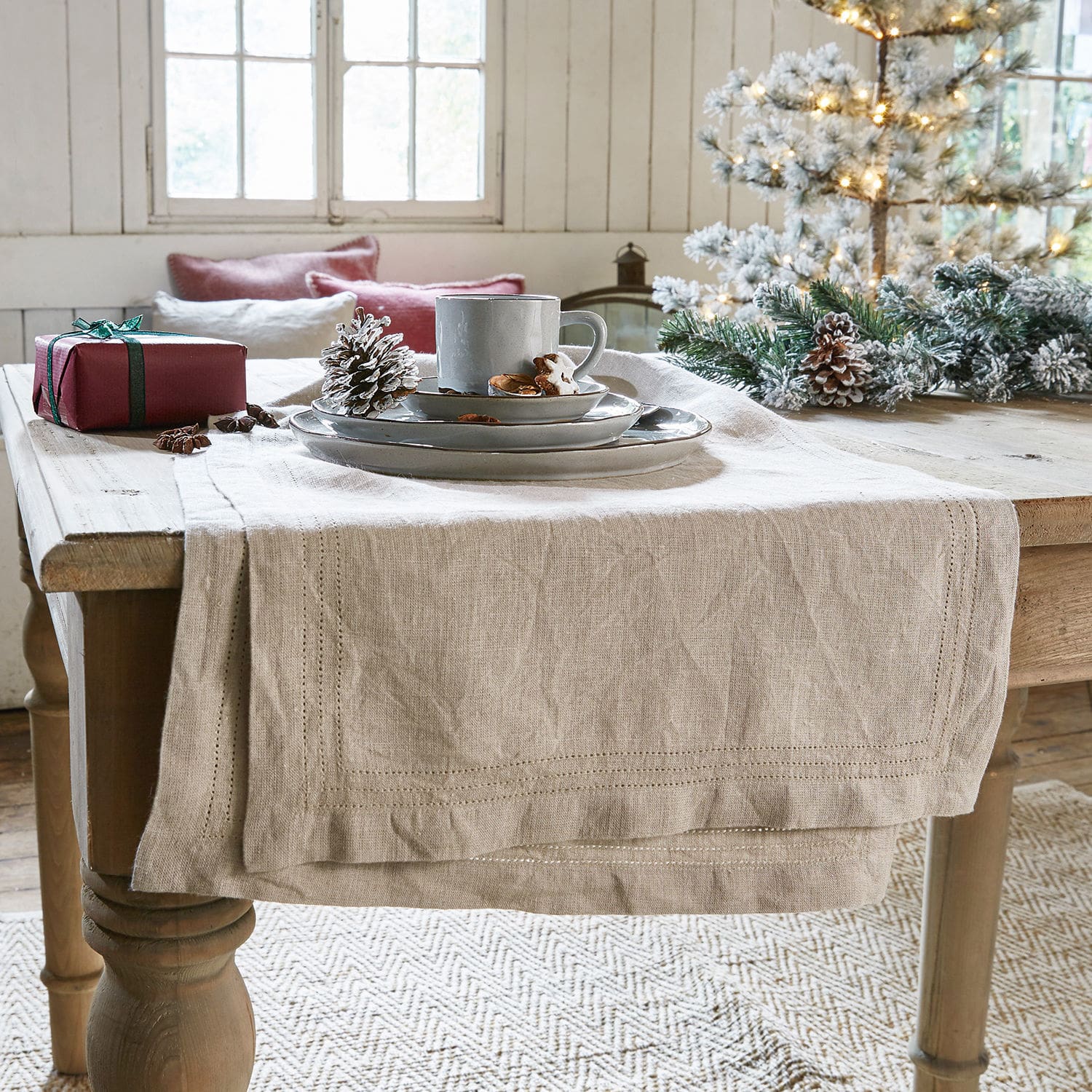 Tischläufer Brion Beiger Leinen-Tischläufer auf Holztisch mit Weihnachtsdekoration und grauem Geschirr