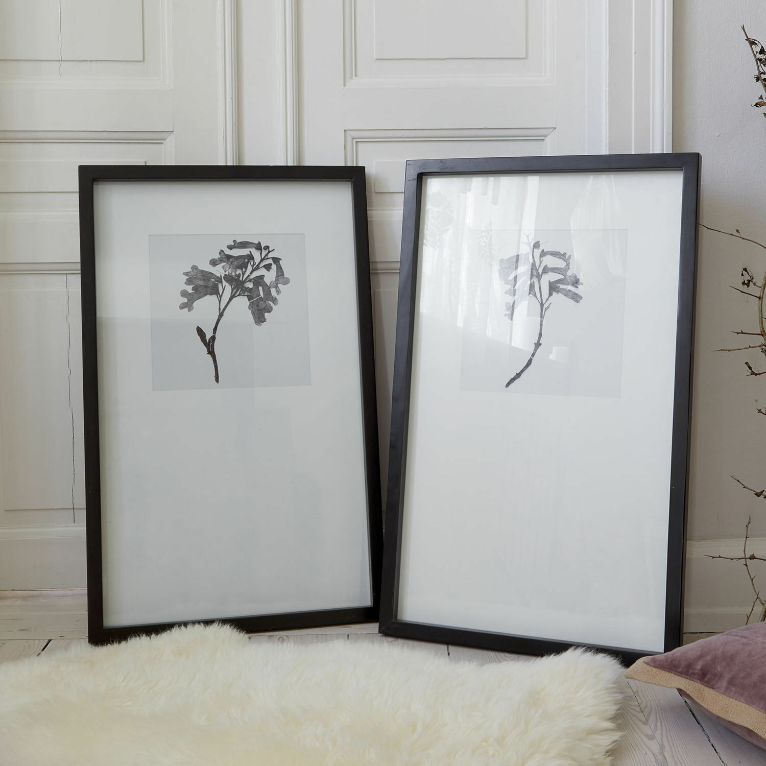Bild 2er Set Virelune Zwei schwarze Bilderrahmen mit Glas und minimalistischen Pflanzenmotiven auf hellem Hintergrund auf Fellteppich