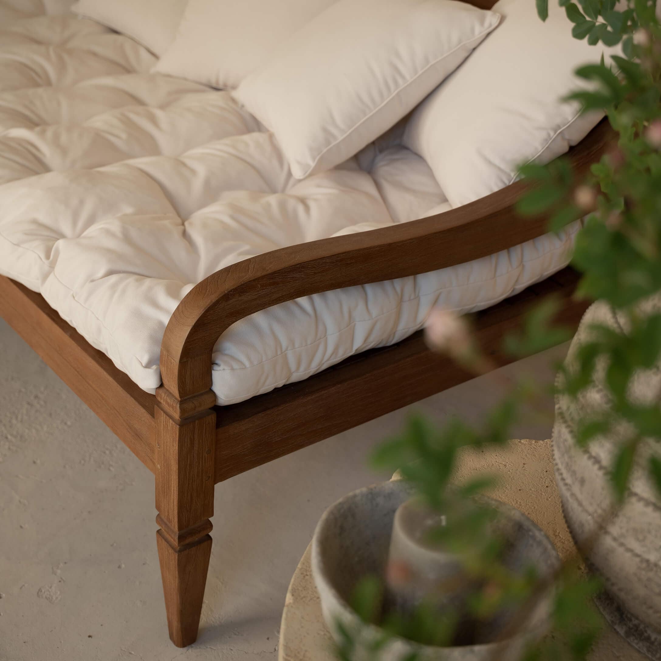 Holzrahmen eines Sofas mit cremefarbener, gesteppter Polsterung und weichen Dekokissen
