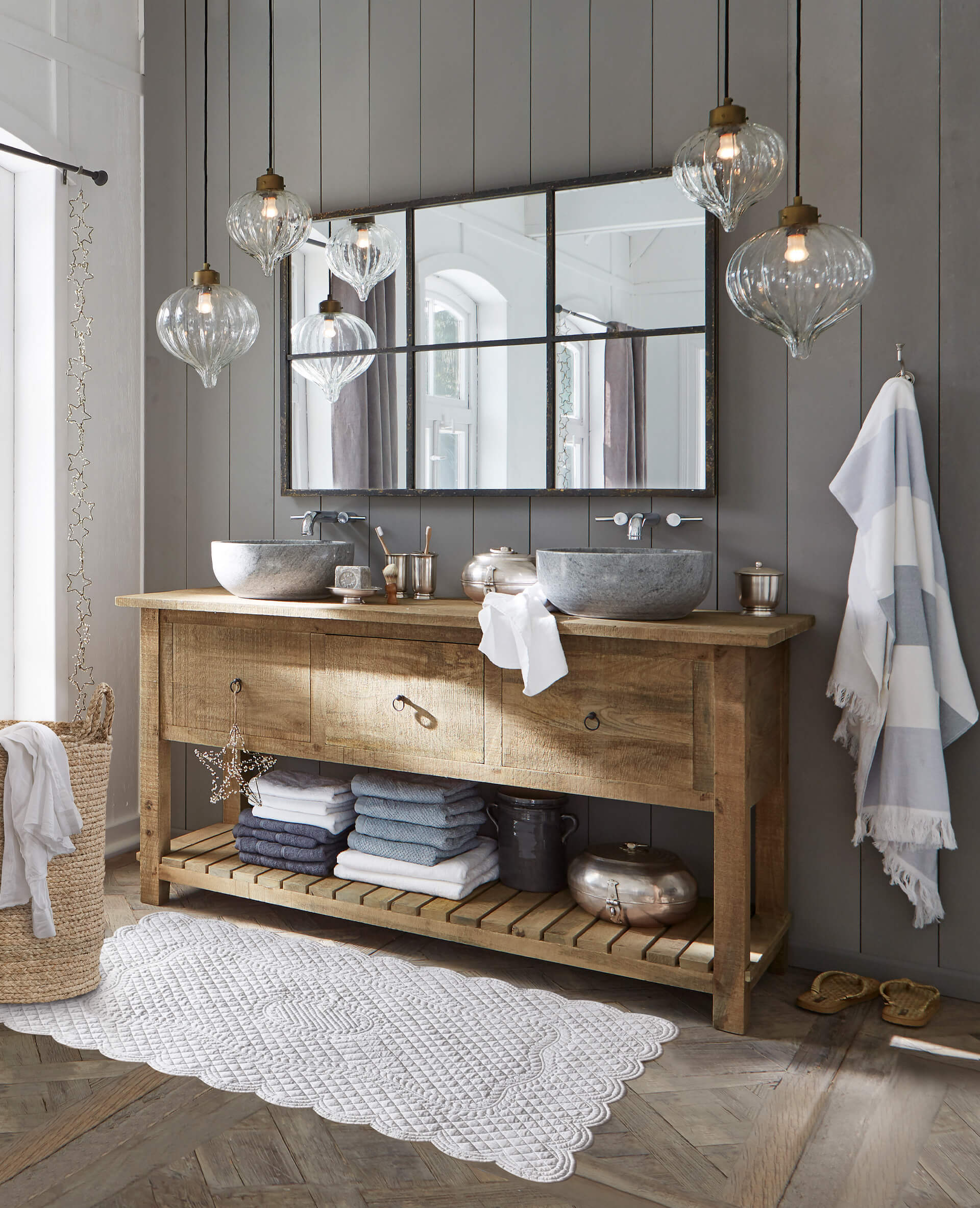 Rustikaler Holz-Waschtisch mit Steinbecken und grauen Handtüchern in einem gemütlichen Badezimmer