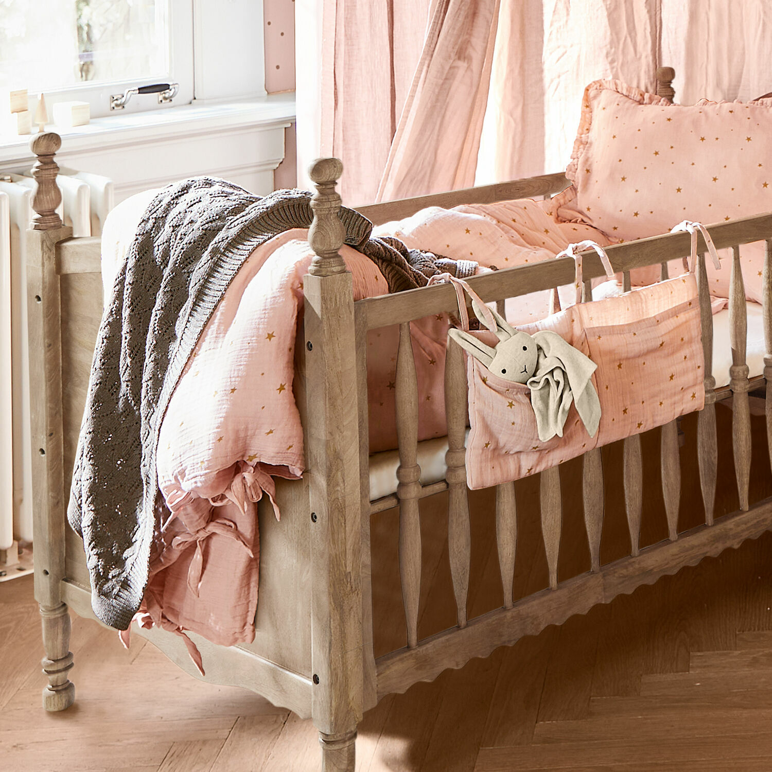 Baby-Bettwäsche Vianne Kinderbett aus Holz mit rosa Sternenbettwäsche und grauer Decke, gemütliches Kinderzimmer