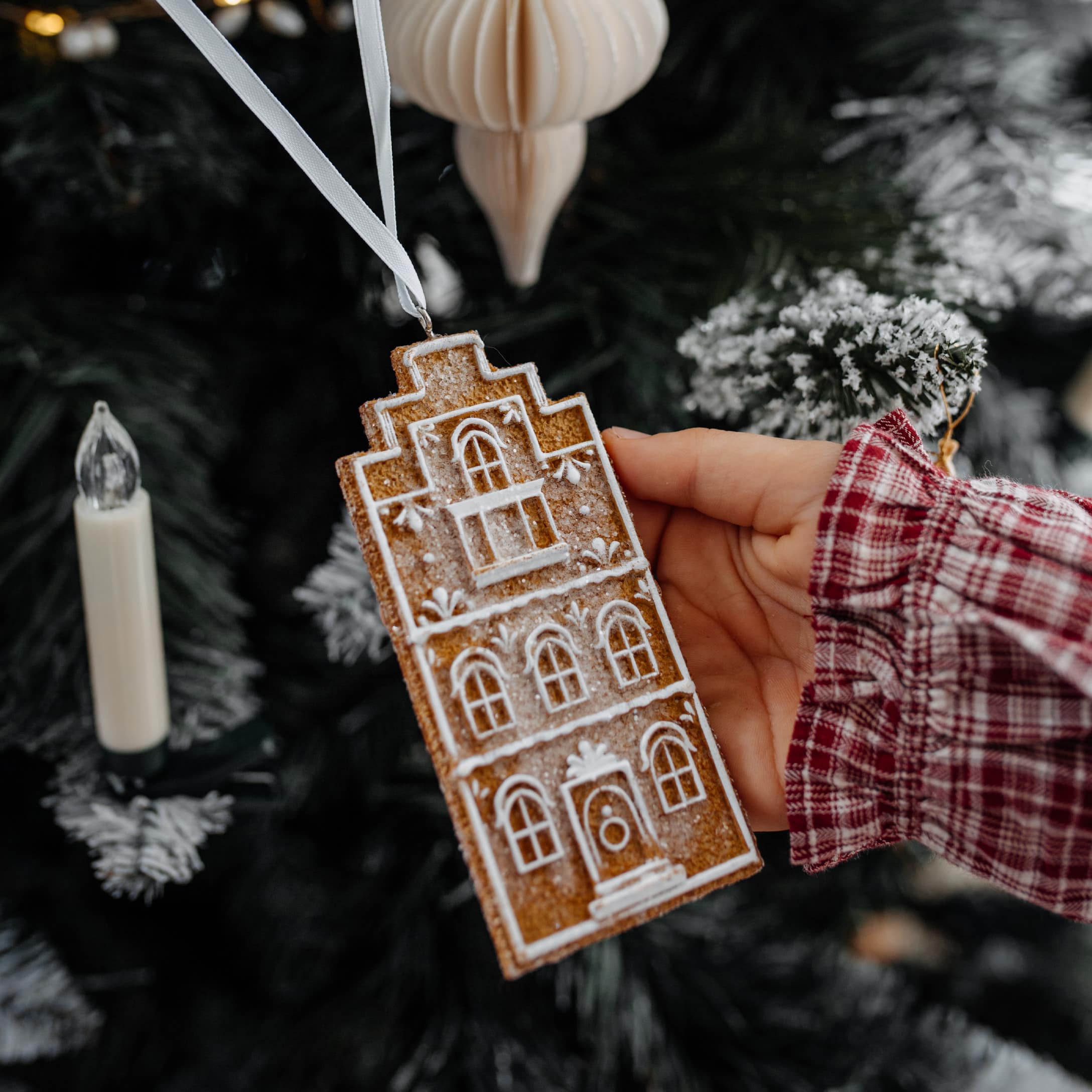 Weihnachtsschmuck als Lebkuchenhaus mit weißem Muster an weißem Band zum Aufhängen