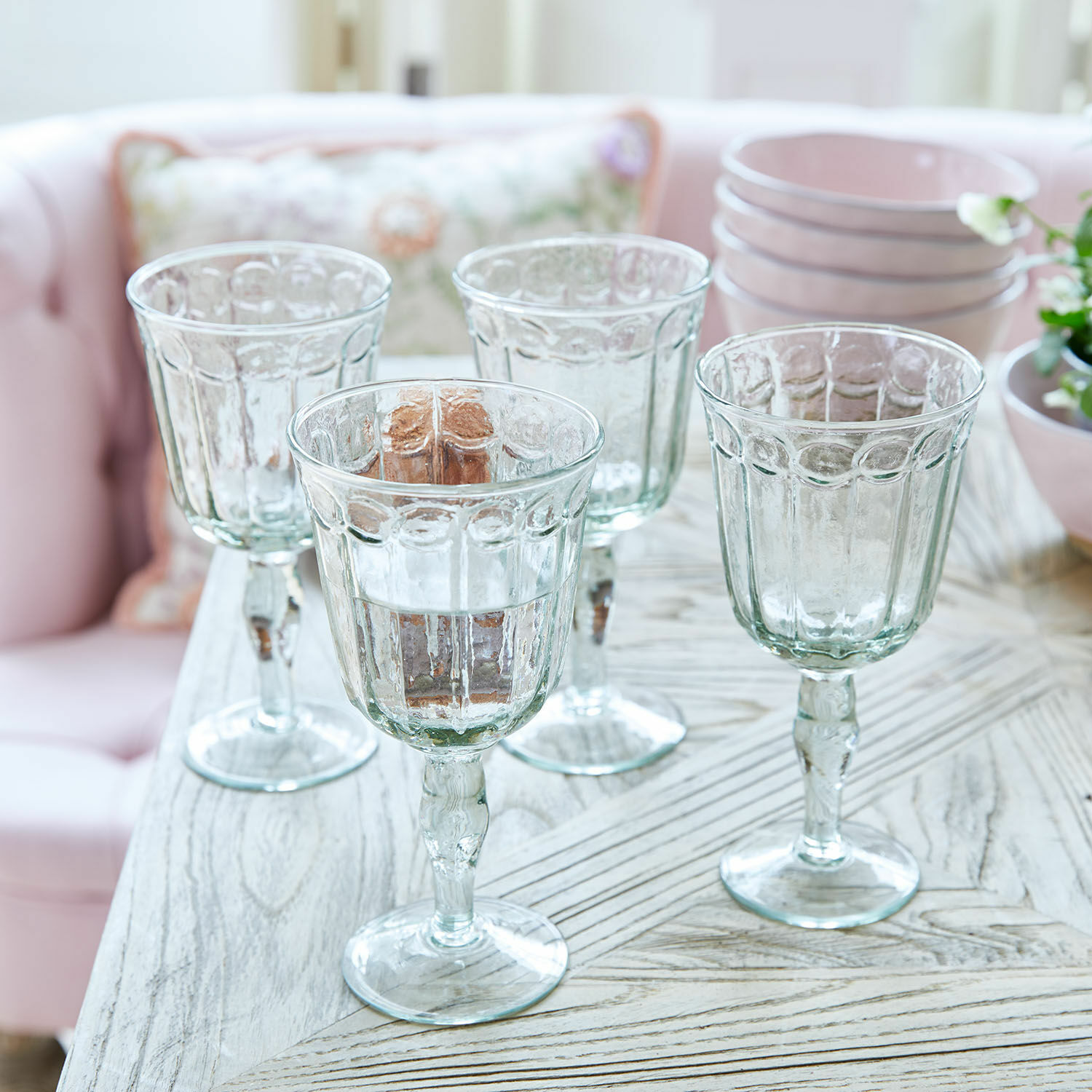 Glas 4er Set Jolielle Vier transparente Gläser mit dekorativem Muster auf einem Holztisch in einem hellen Raum