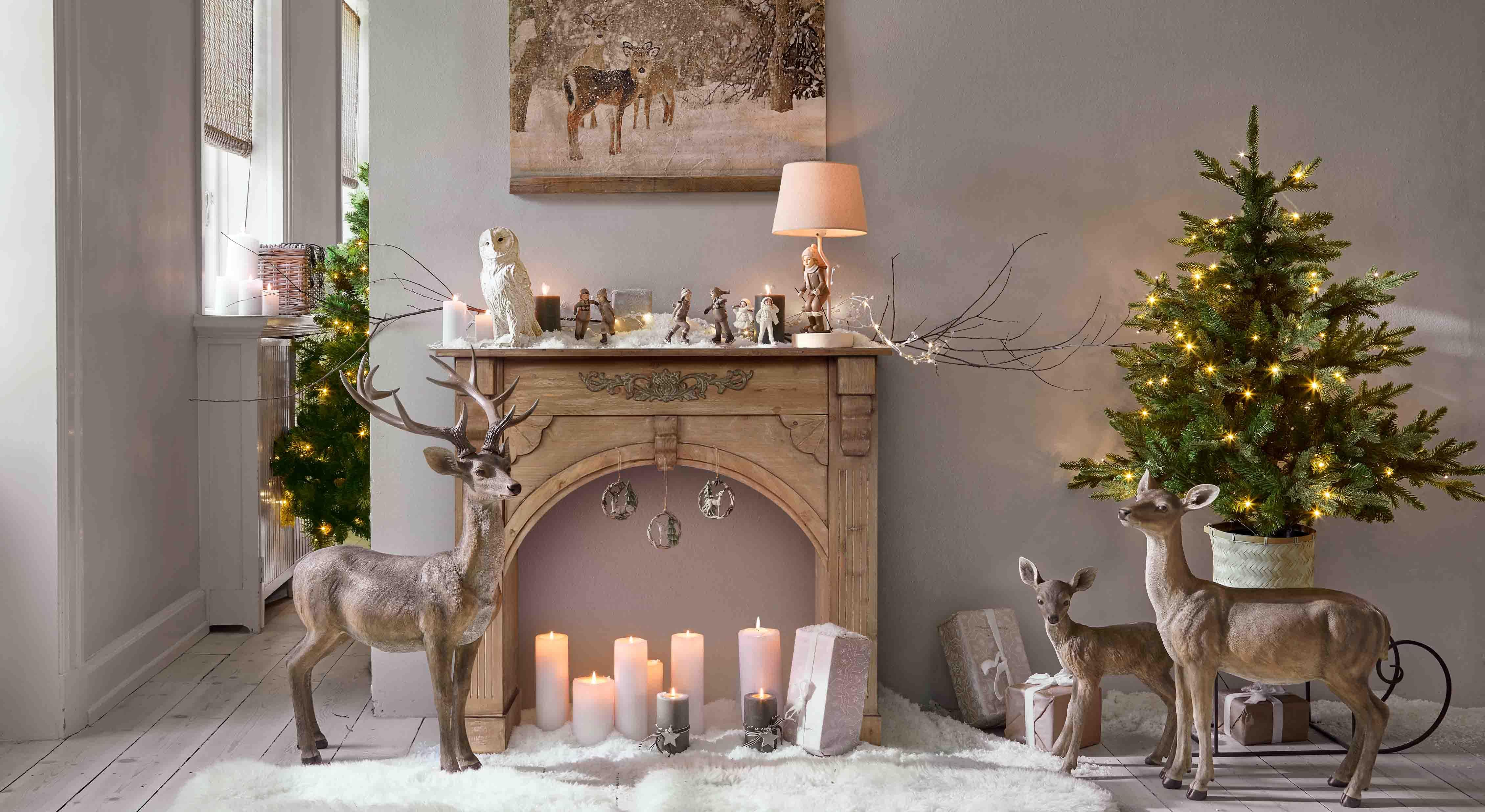 Weihnachtsdekoration mit braunen Hirschfiguren, Kerzen und grünem LED-beleuchtetem Tannenbaum