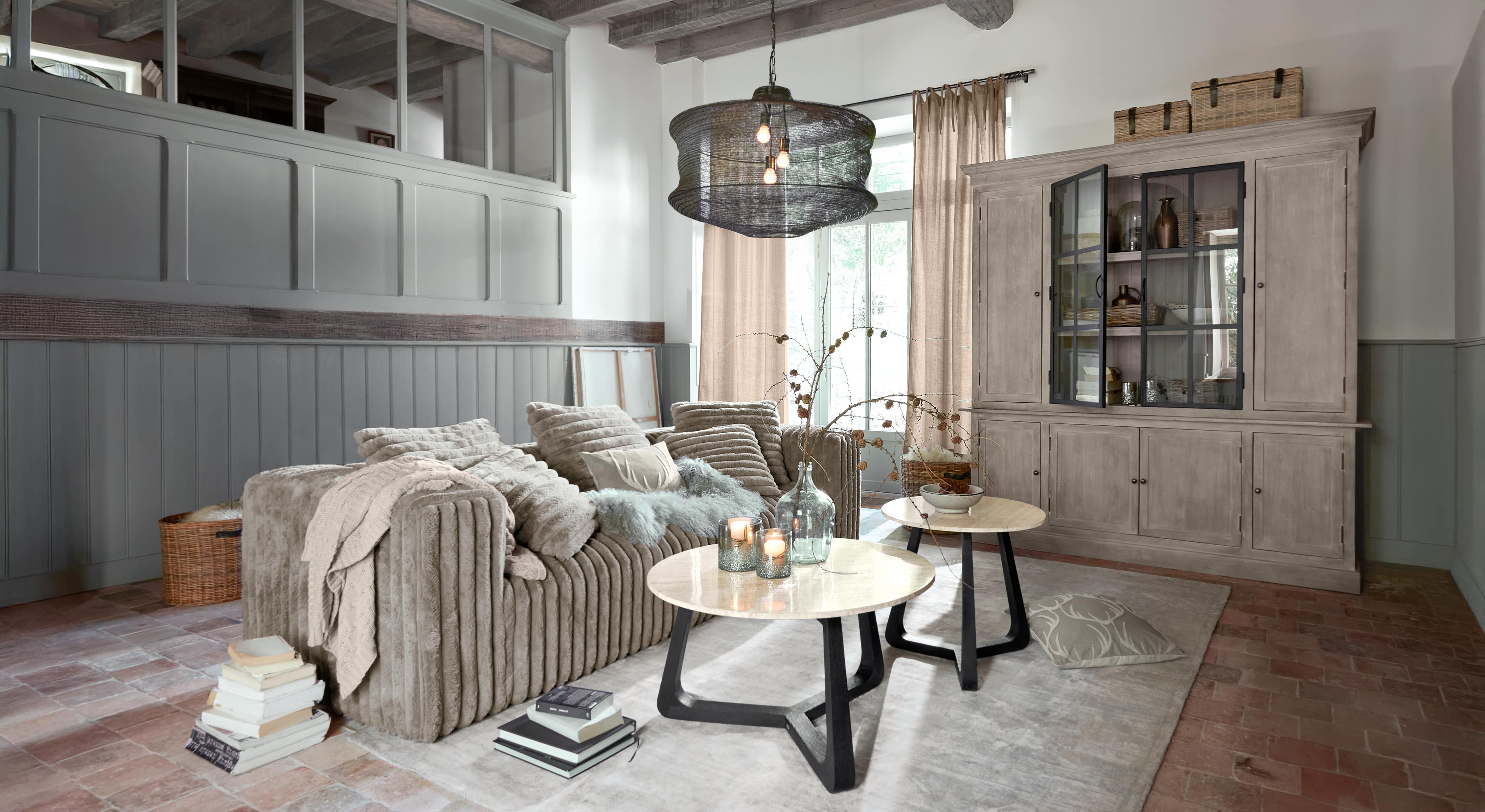 Gemütliches Wohnzimmer mit beigem Sofa aus weichem Stoff und zwei runden Couchtischen mit Marmorplatten