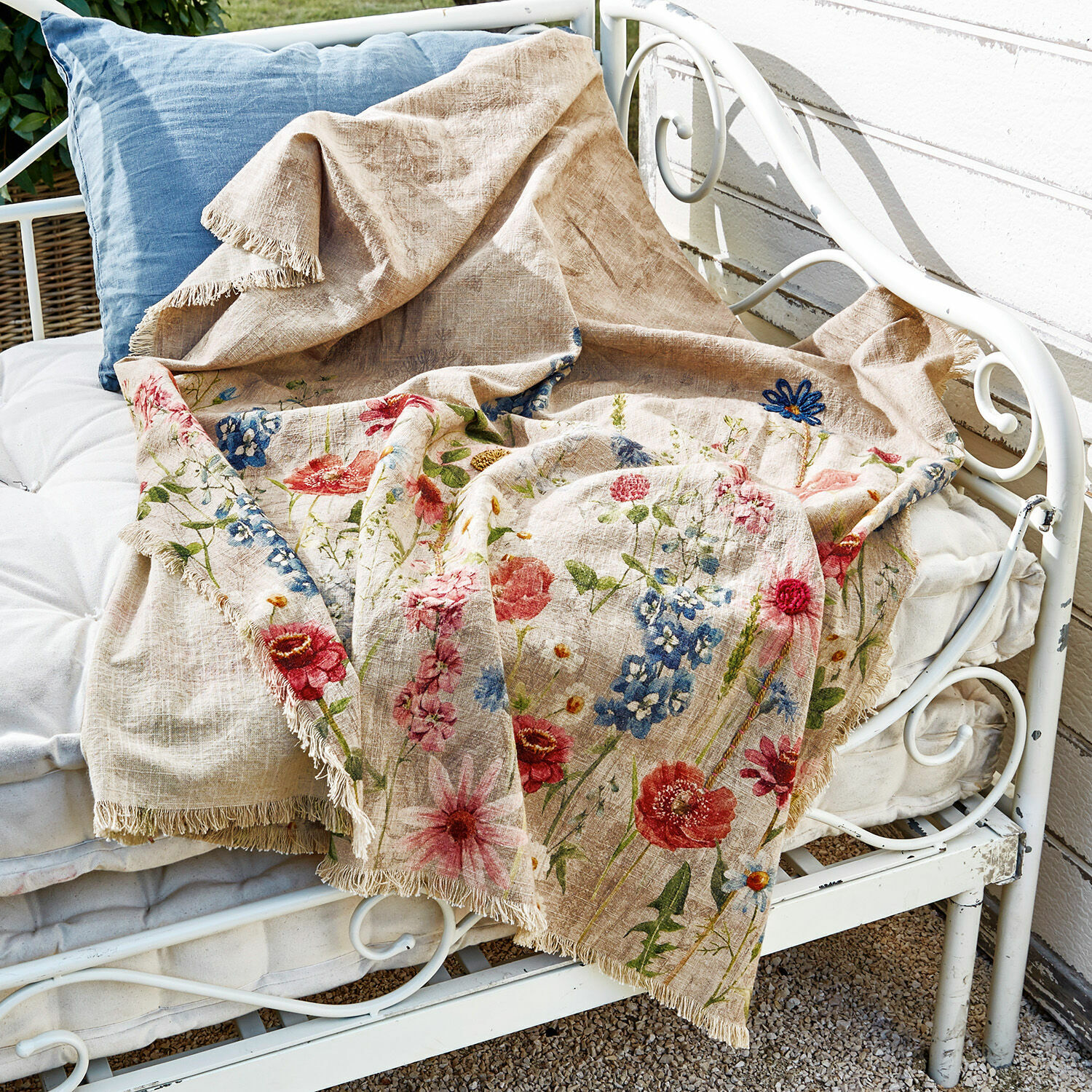 Plaid Eleonoire Beige Leinen-Decke mit buntem Blumenmuster und Fransen auf weisser Metallbank
