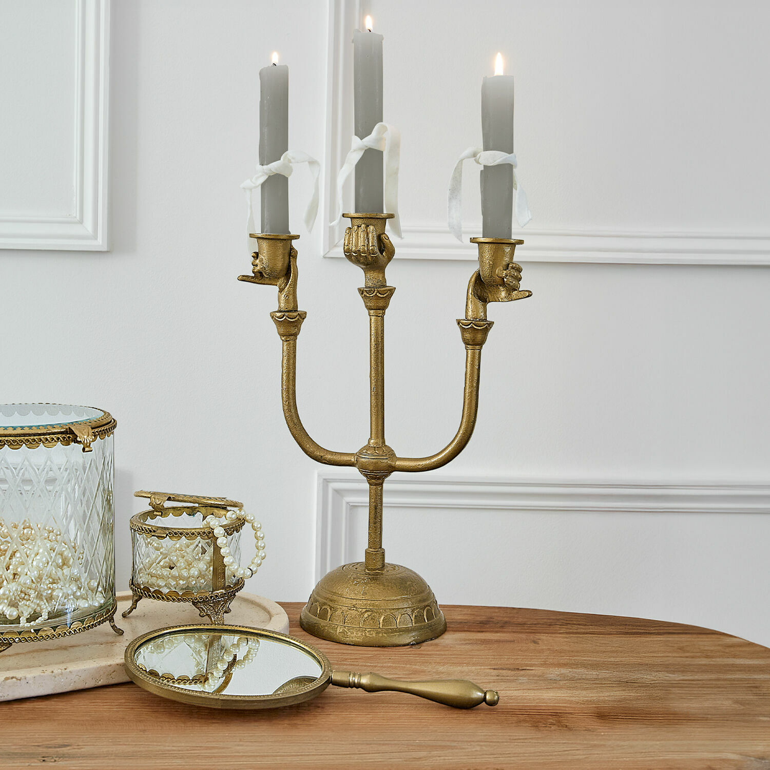 Kerzenständer Joravel Goldener Kerzenhalter mit drei grauen Kerzen und handförmigen Haltern auf dem Holztisch