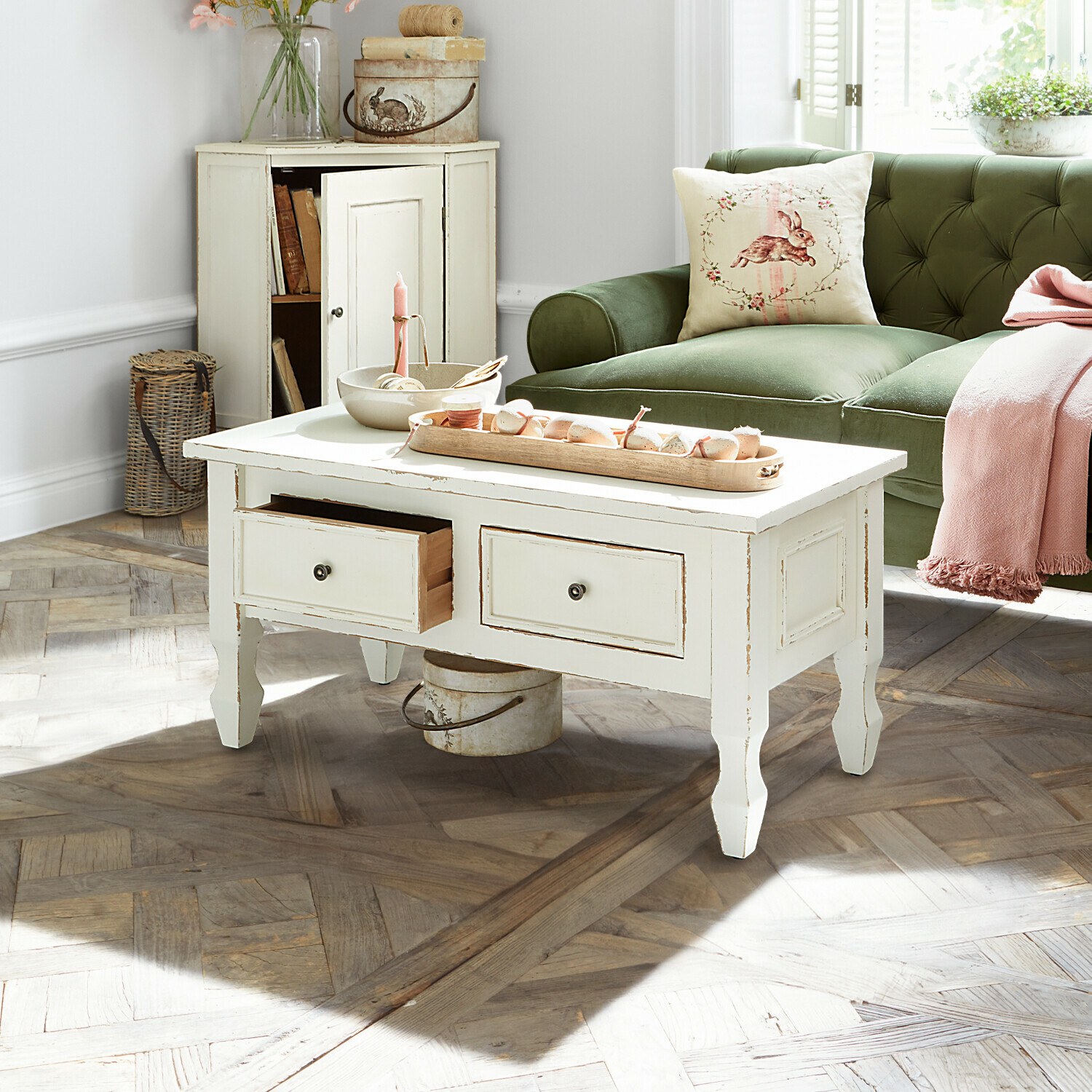 Couchtisch Yurielka Weißer Holztisch im Vintage-Stil mit Schubladen in hellem Wohnzimmer mit grünem Sofa
