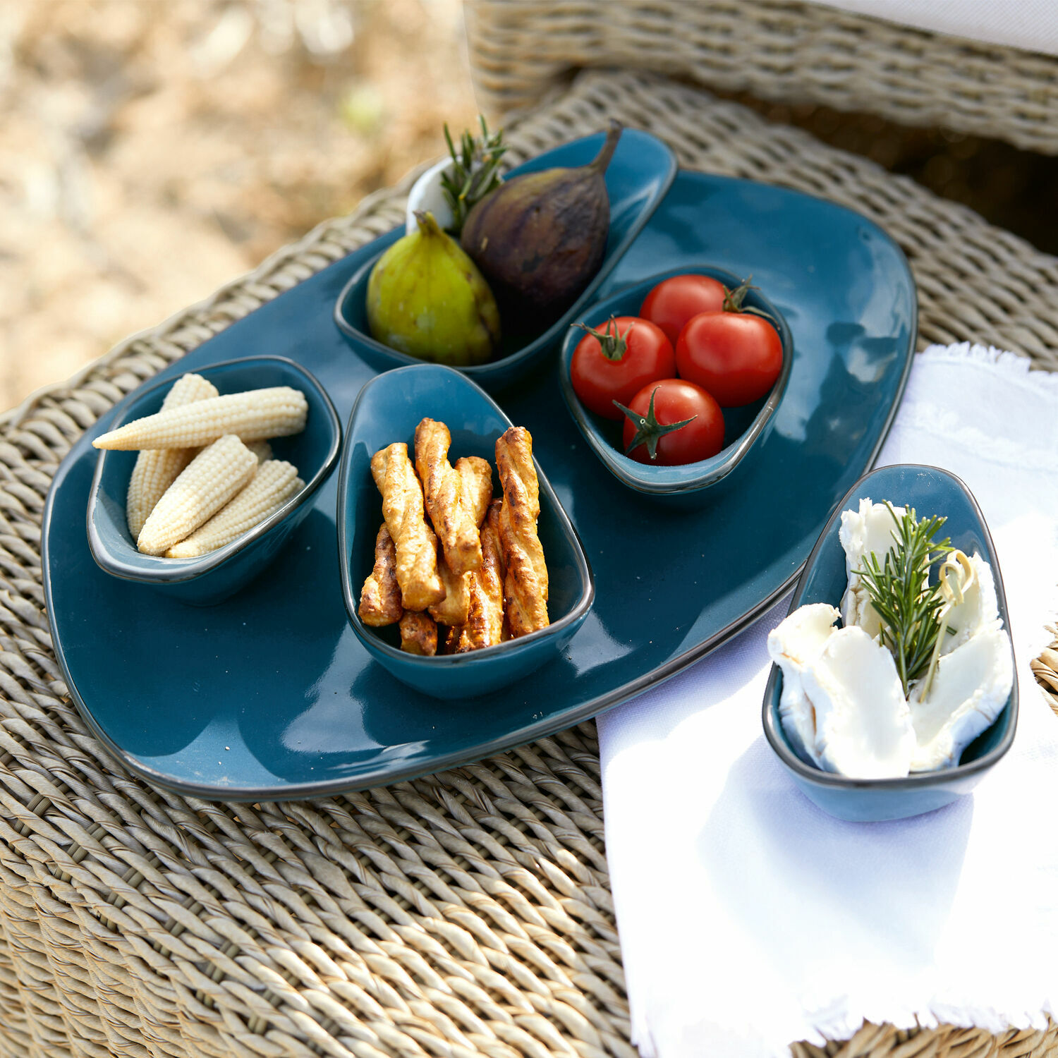 Servierschälchen 6er Set Biarré Set aus blauen Keramikschalen und Platte mit Snacks auf geflochtenem Tisch