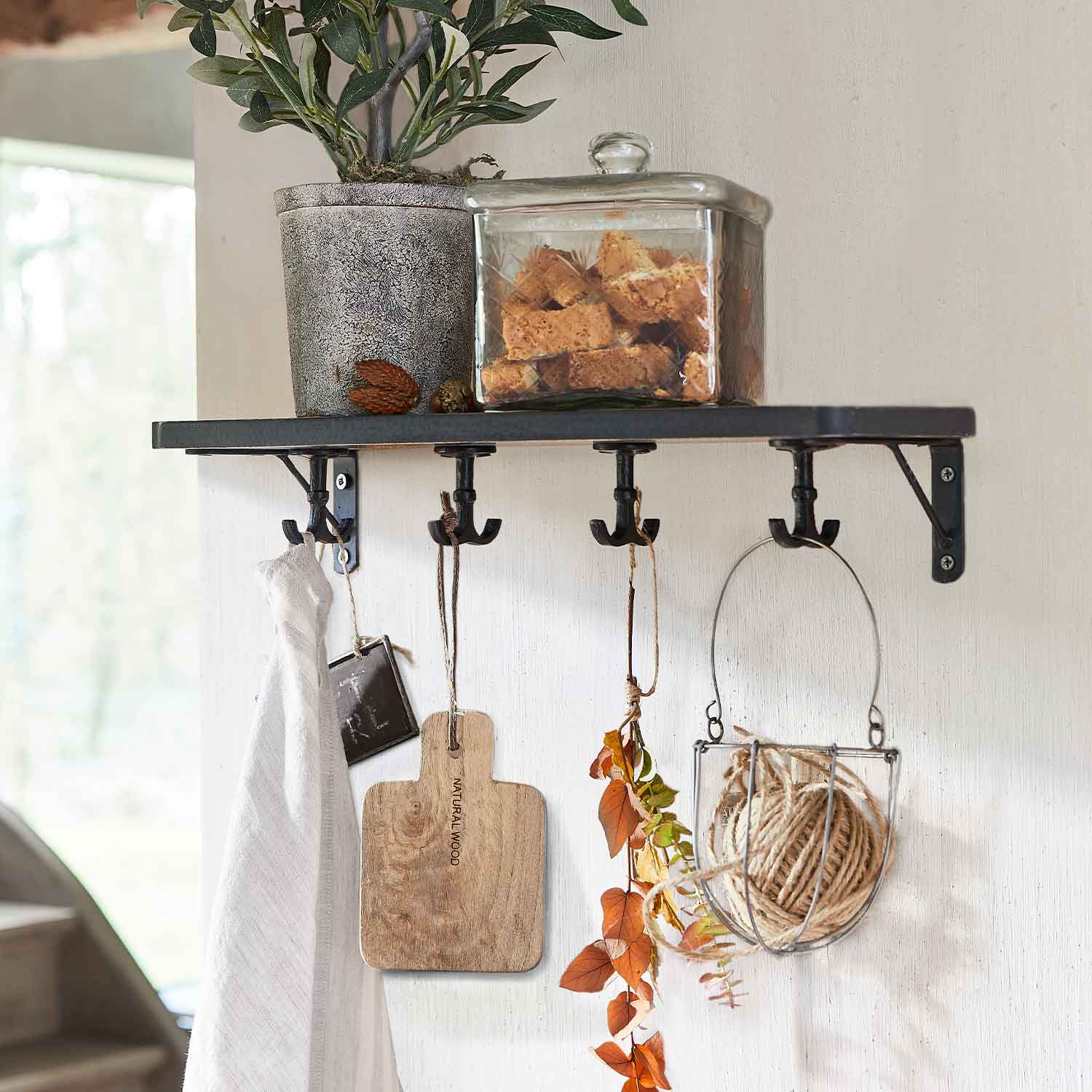 Schwarzes Metallwandregal mit Haken, Blumentopf und Glasdose mit Keksen darauf