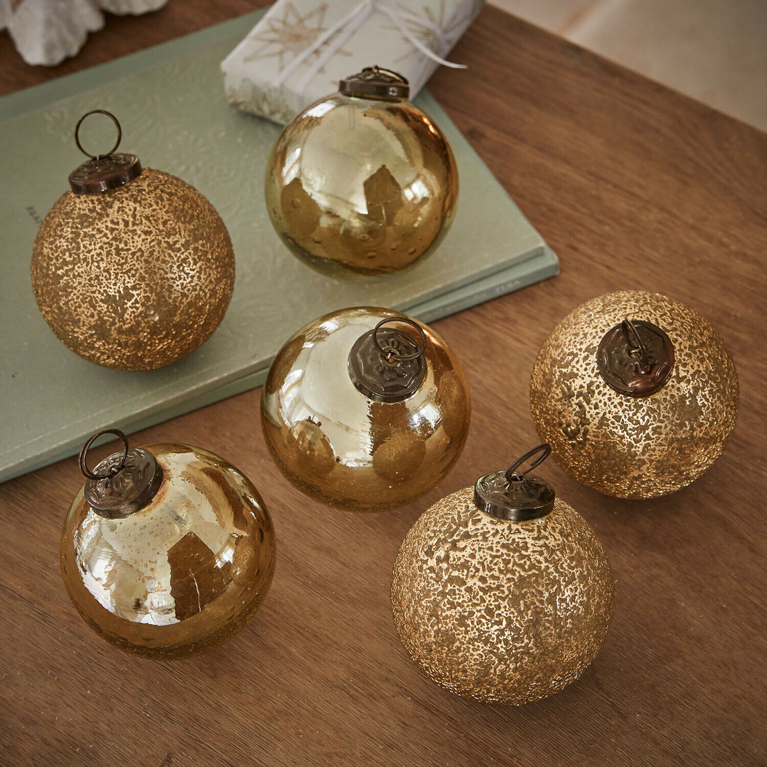 Weihnachtskugel 6er Set Fioravino Set mit sechs goldfarbenen Weihnachtskugeln aus Glas mit verschiedenen Oberflächen auf Holztisch