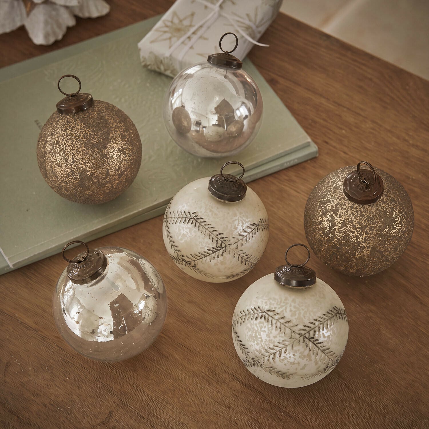 Weihnachtskugel 6er Set Fioravino Set mit sechs goldfarbenen Weihnachtskugeln aus Glas mit verschiedenen Oberflächen auf Holztisch
