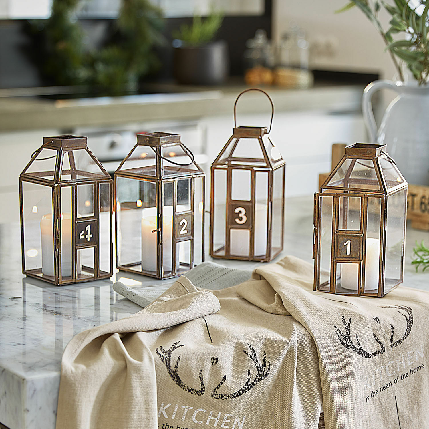 Laterne 4er Set Lythoria Vier nummerierte Metalllaternen mit Kerzen auf einer Marmorarbeitsplatte in der Küche