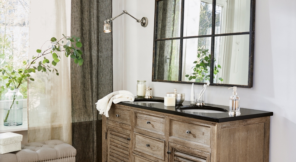 Holz-Badezimmerschrank mit schwarzer Arbeitsplatte und Doppelwaschbecken, Spiegel und Pflanze im natürlichen Stil