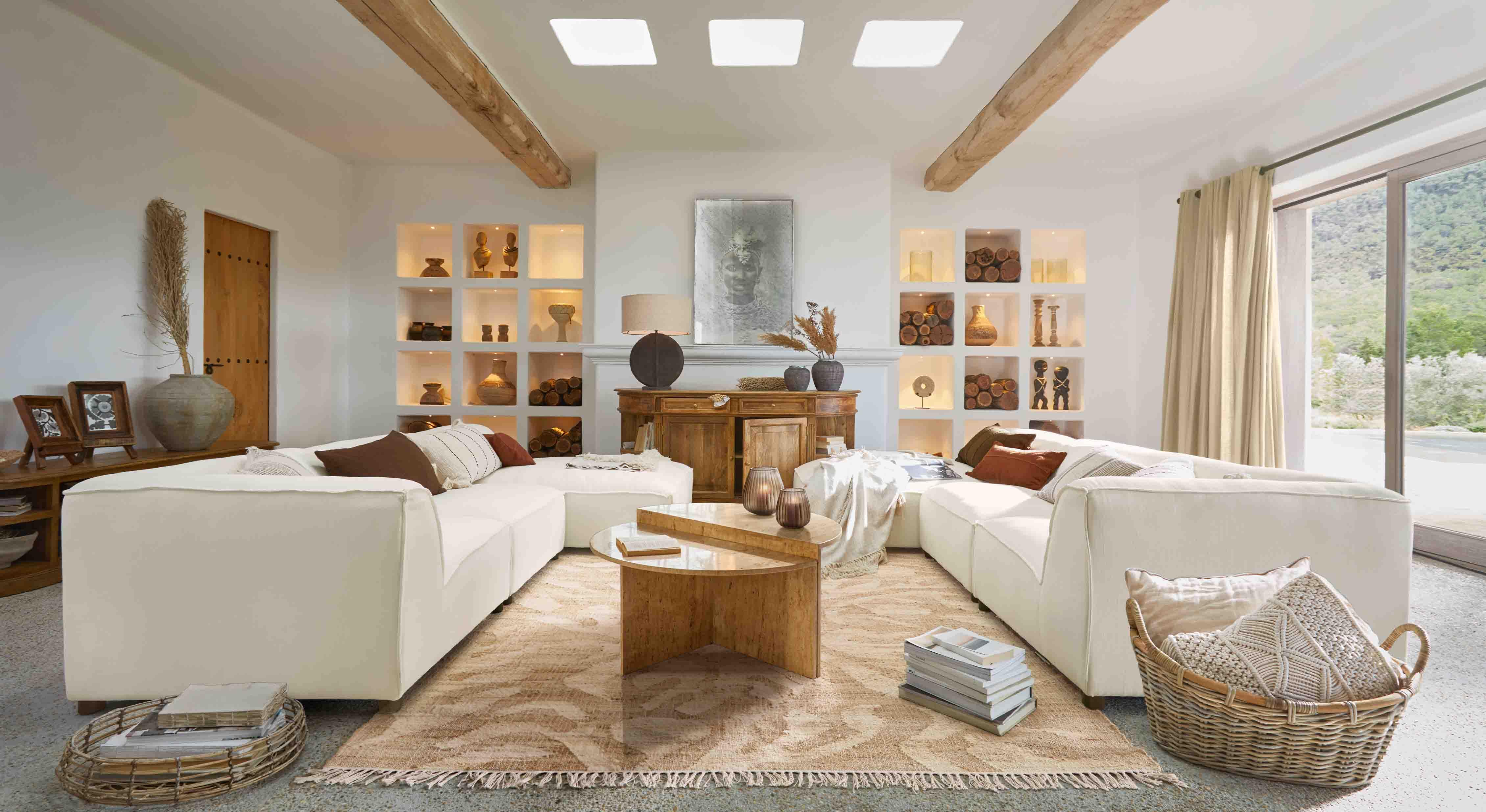 Geräumiges Wohnzimmer mit weissem Ecksofa, Holztisch und warmen Naturdekorationen
