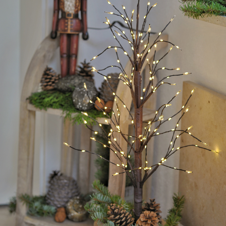 Dekorativer Lichterbaum aus braunem Material mit warmweissen LED-Lichtern und Tannenzapfen